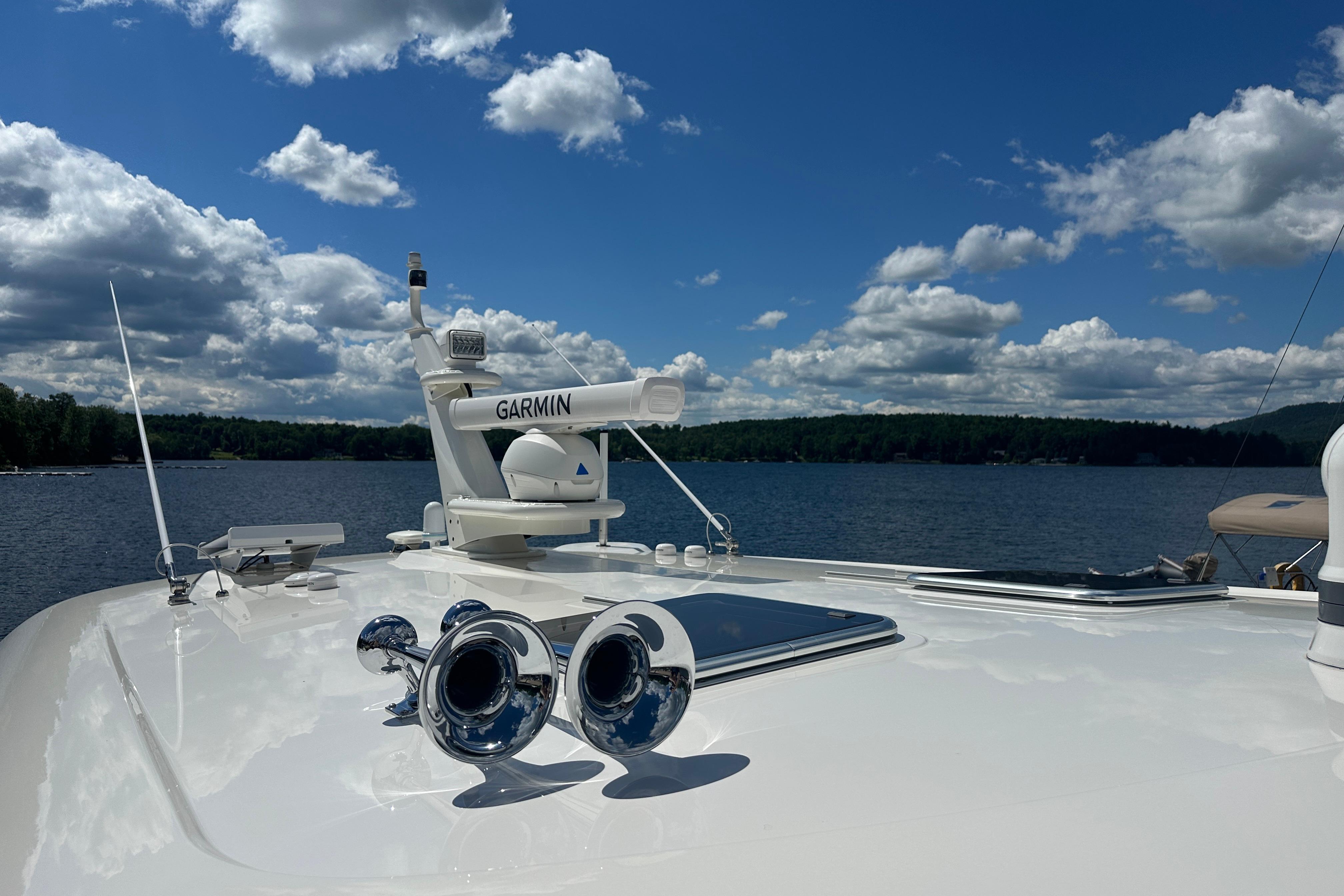 2025 Sabre 48 Salon Express yacht with Garmin equipment on a serene lake under a cloudy sky.