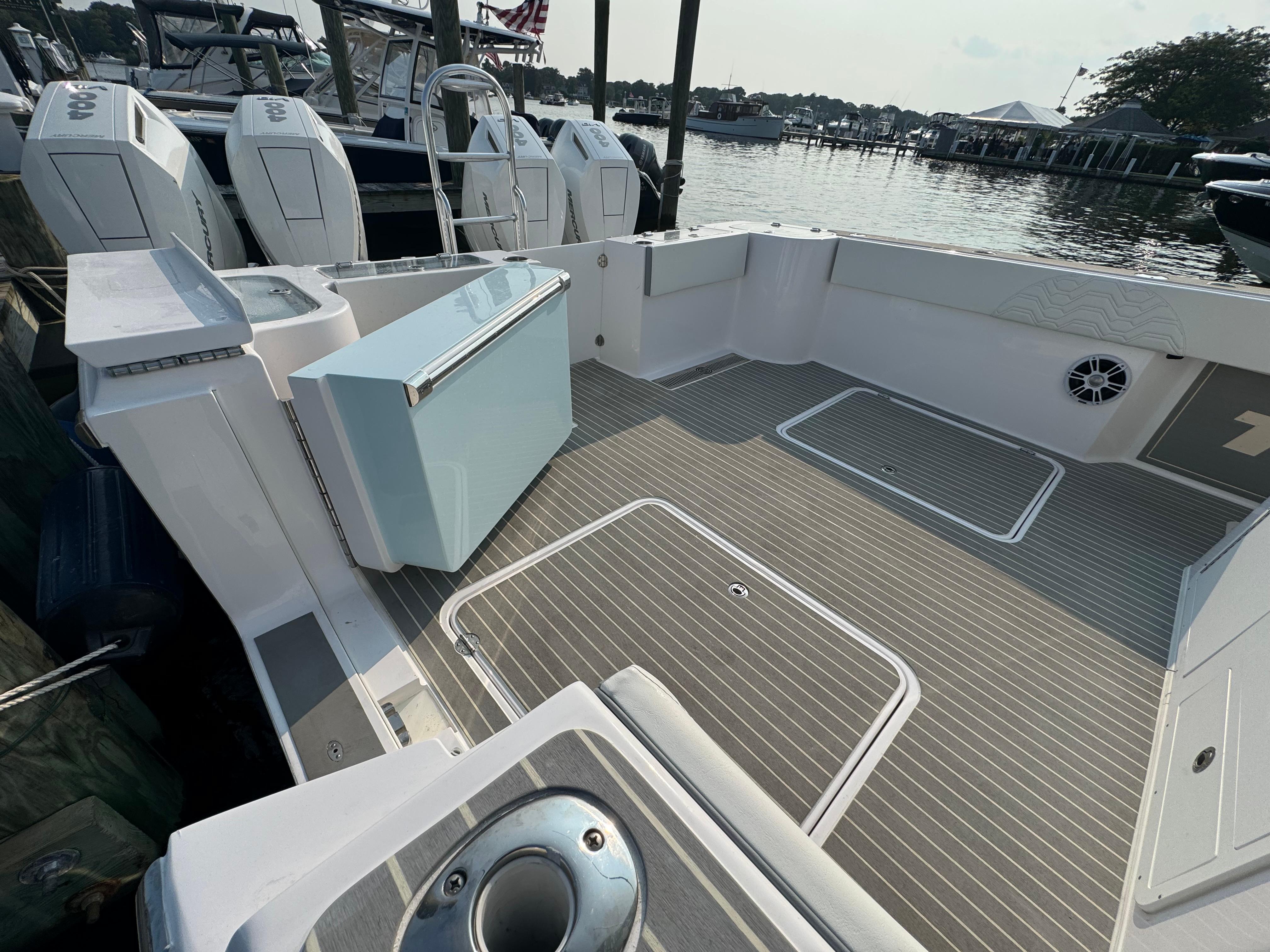 2025 Twin Vee 400 GFX boat deck with storage compartments and outboard motors at a marina.