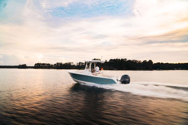 2024 Sea Hunt Ultra 234 boat cruising on a serene lake at sunset.