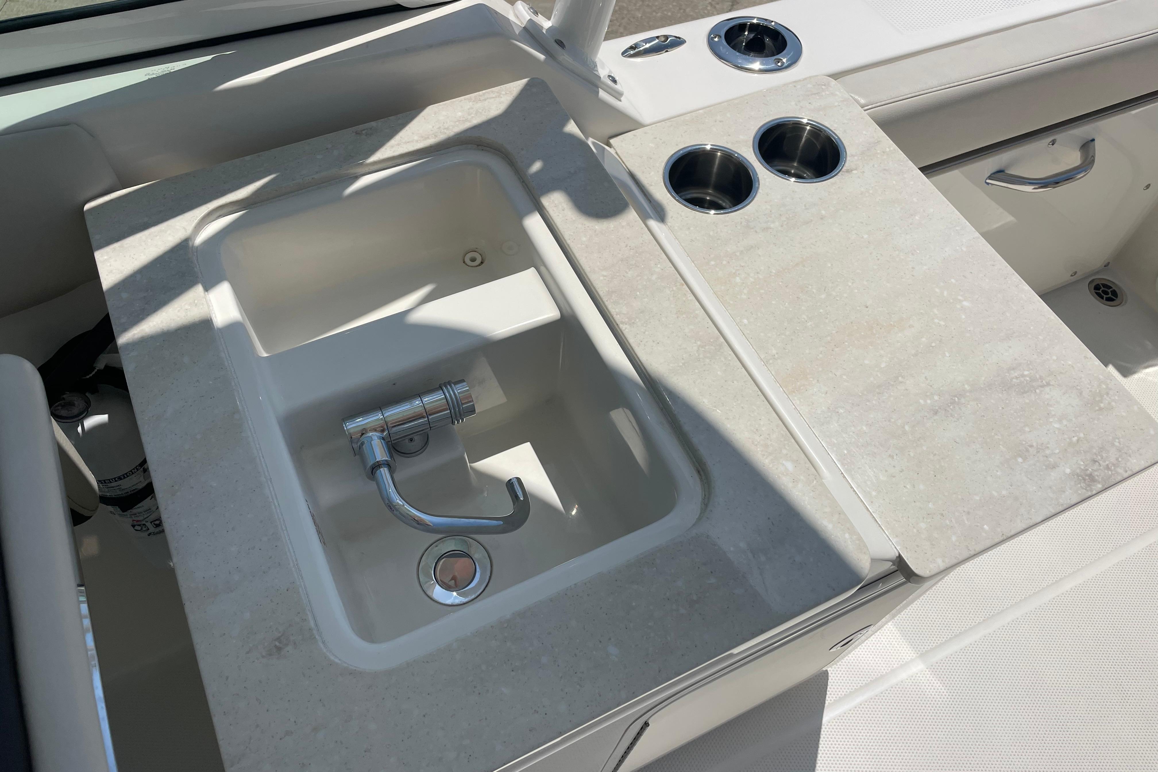 Sailfish 245 DC 2022 boat sink with faucet and cup holders on deck.