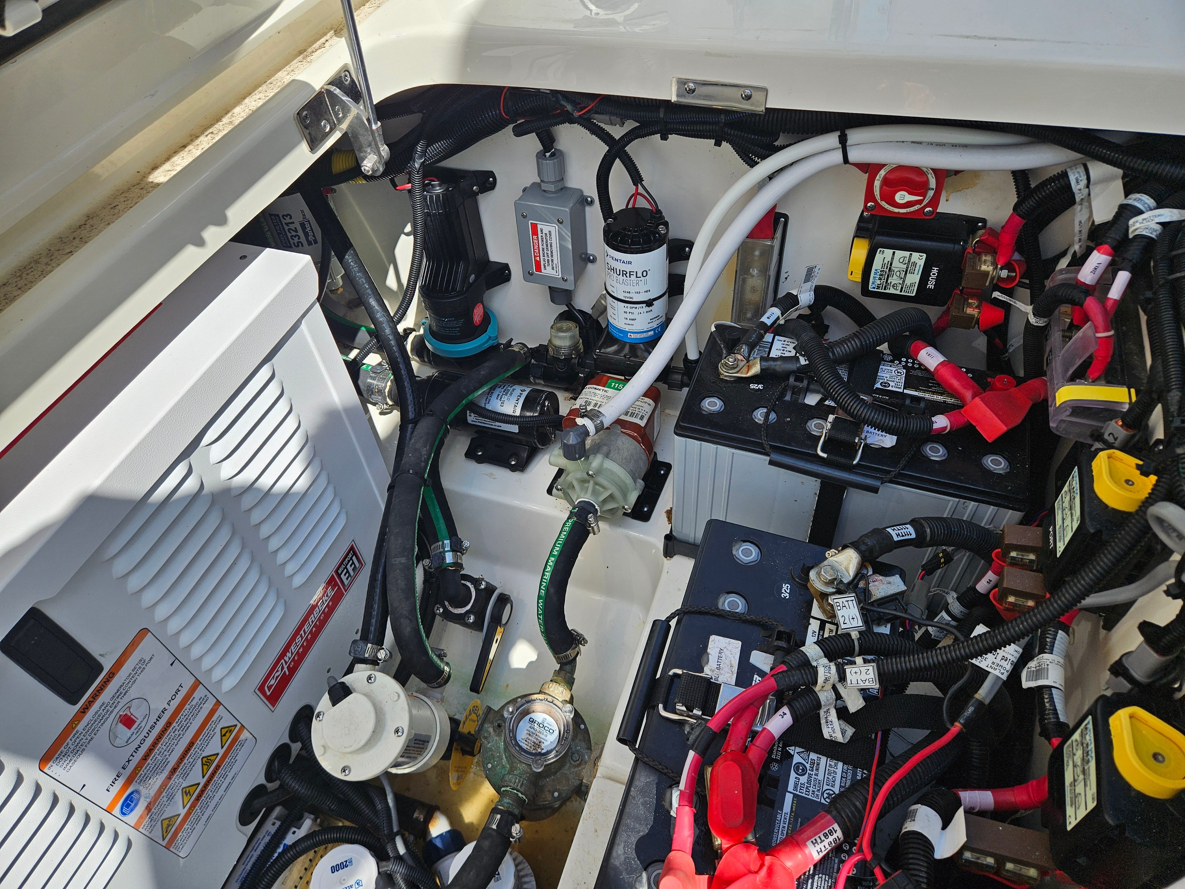 View of the engine compartment of a Boston Whaler 325 Conquest with batteries and wiring.