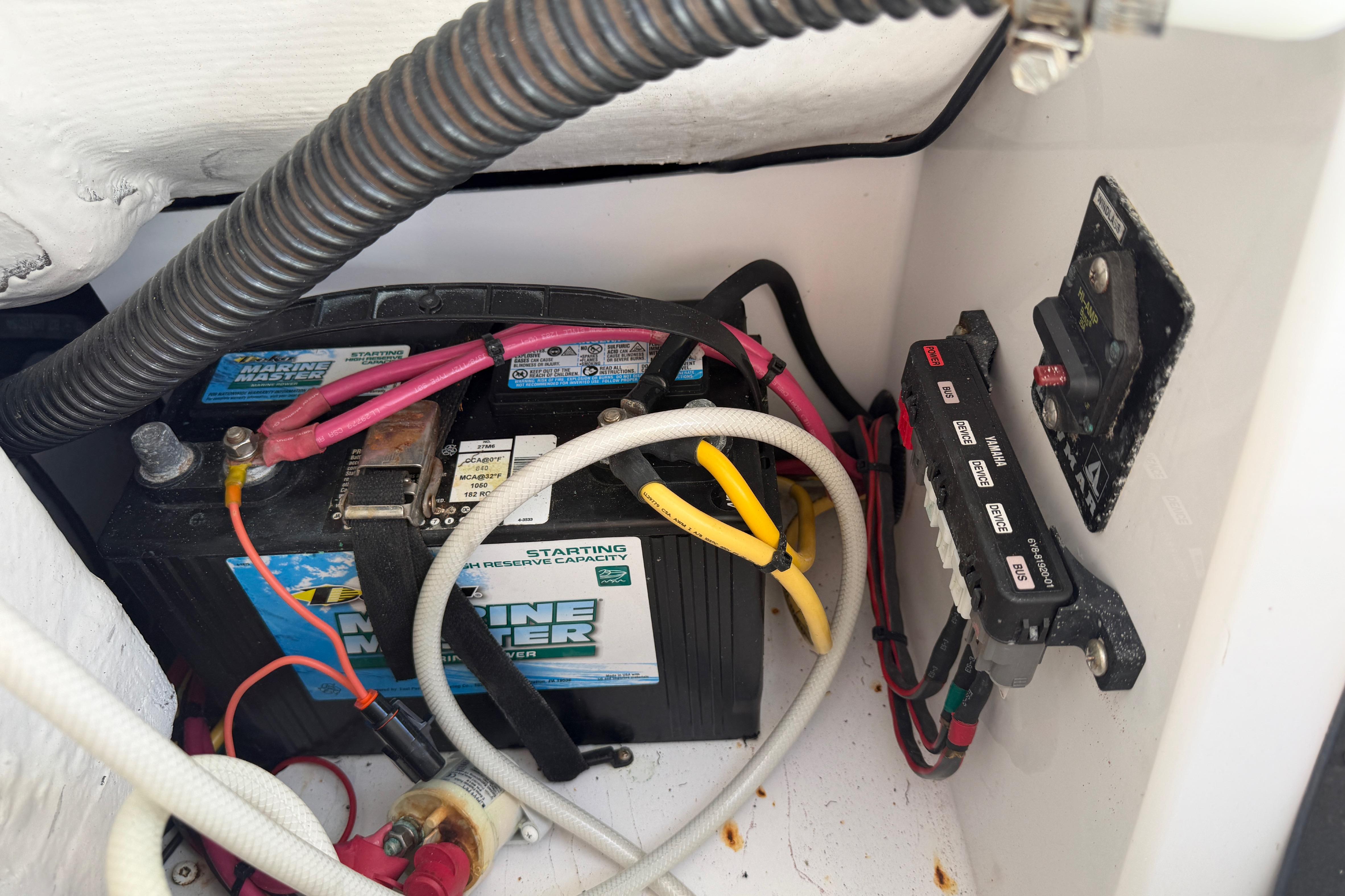 Battery compartment of a 2006 Southport 26 Center Console boat with wiring and fuse panel.