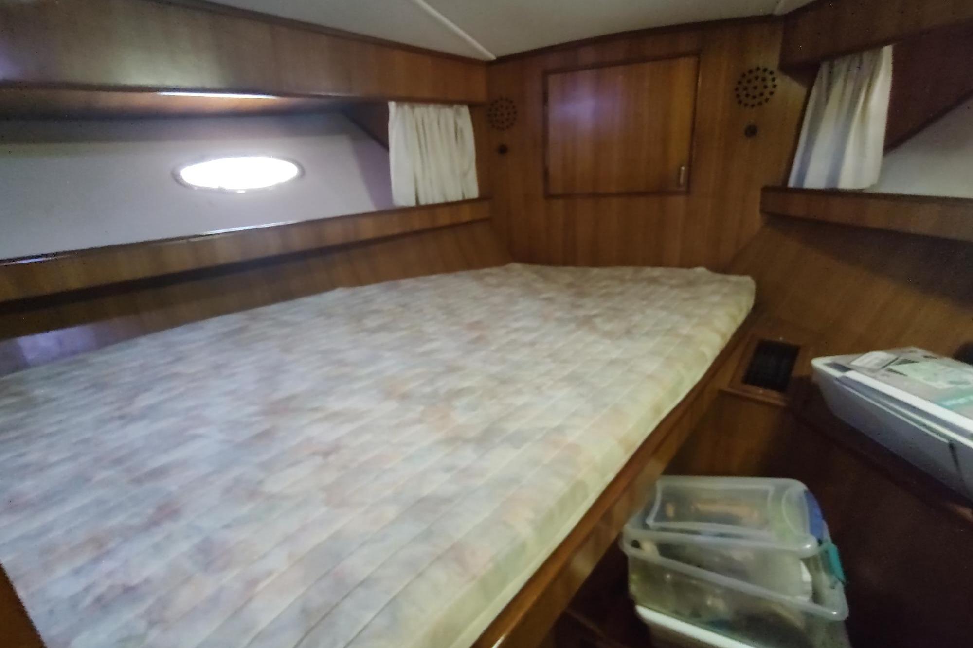 Cozy cabin interior of 1989 Hyatt Double Cabin Motoryacht with wooden paneling and bed.