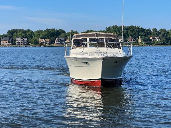 A 1985 Viking 35 Express cruising on calm water with houses in the background.