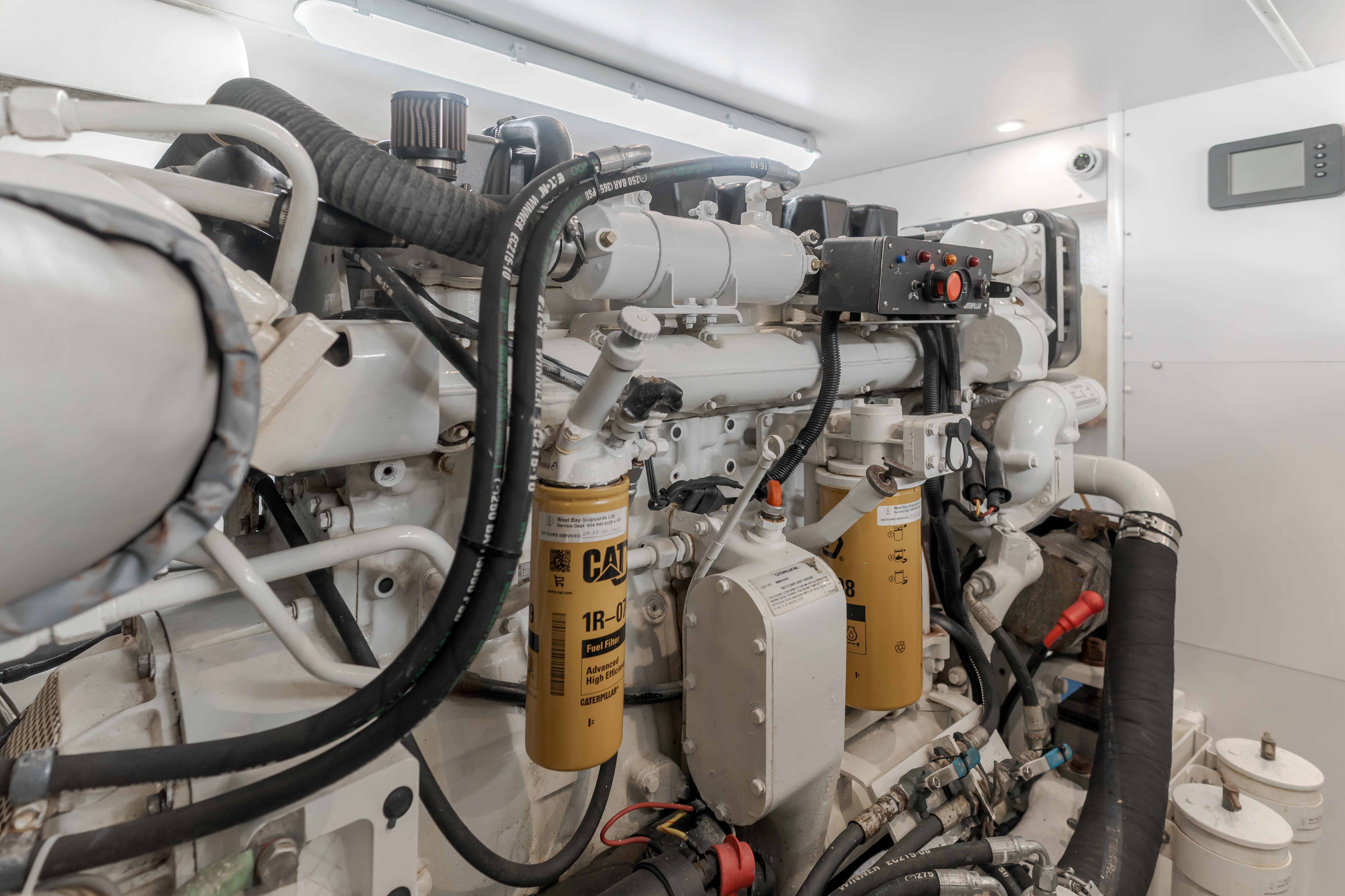 Engine room of 2006 West Bay 64 yacht, featuring Caterpillar components and intricate piping.