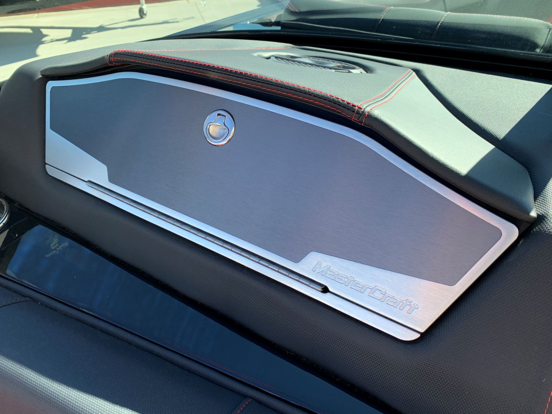 Close-up of a MasterCraft X24 dashboard with silver accent and red stitching.
