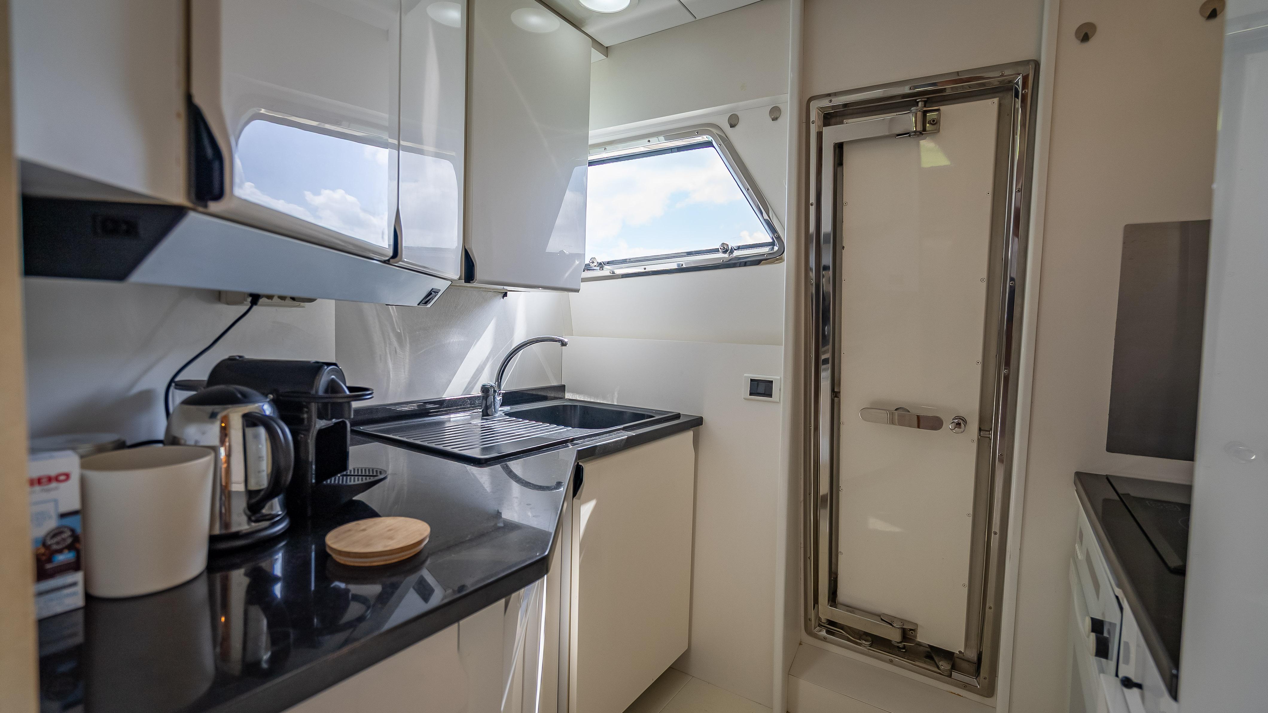 Compact kitchen in a 1995 Sanlorenzo 62 yacht with modern appliances and sleek design.