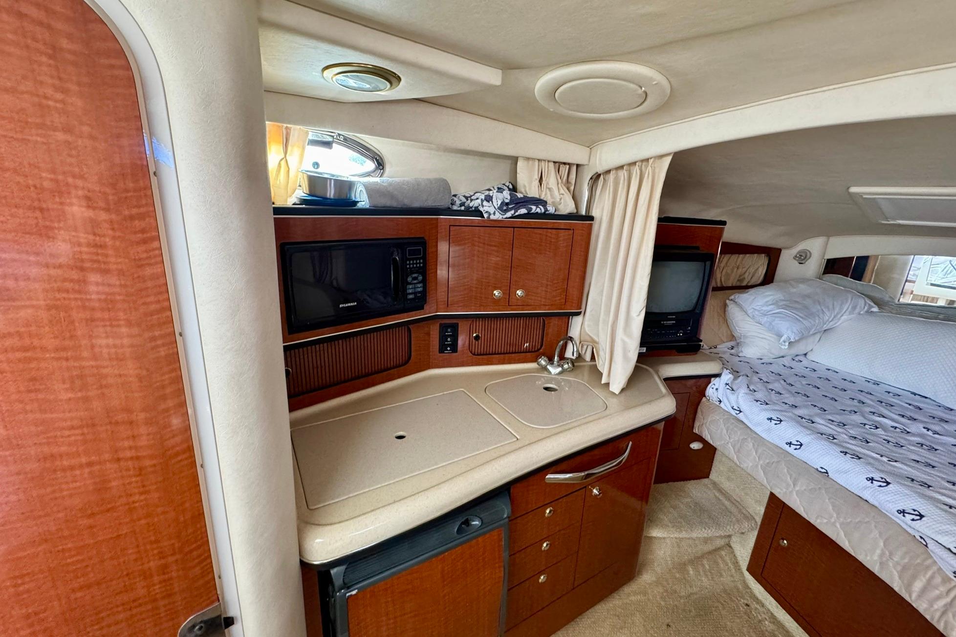 2003 Sea Ray 300 Sundancer cabin interior with kitchenette and bed.