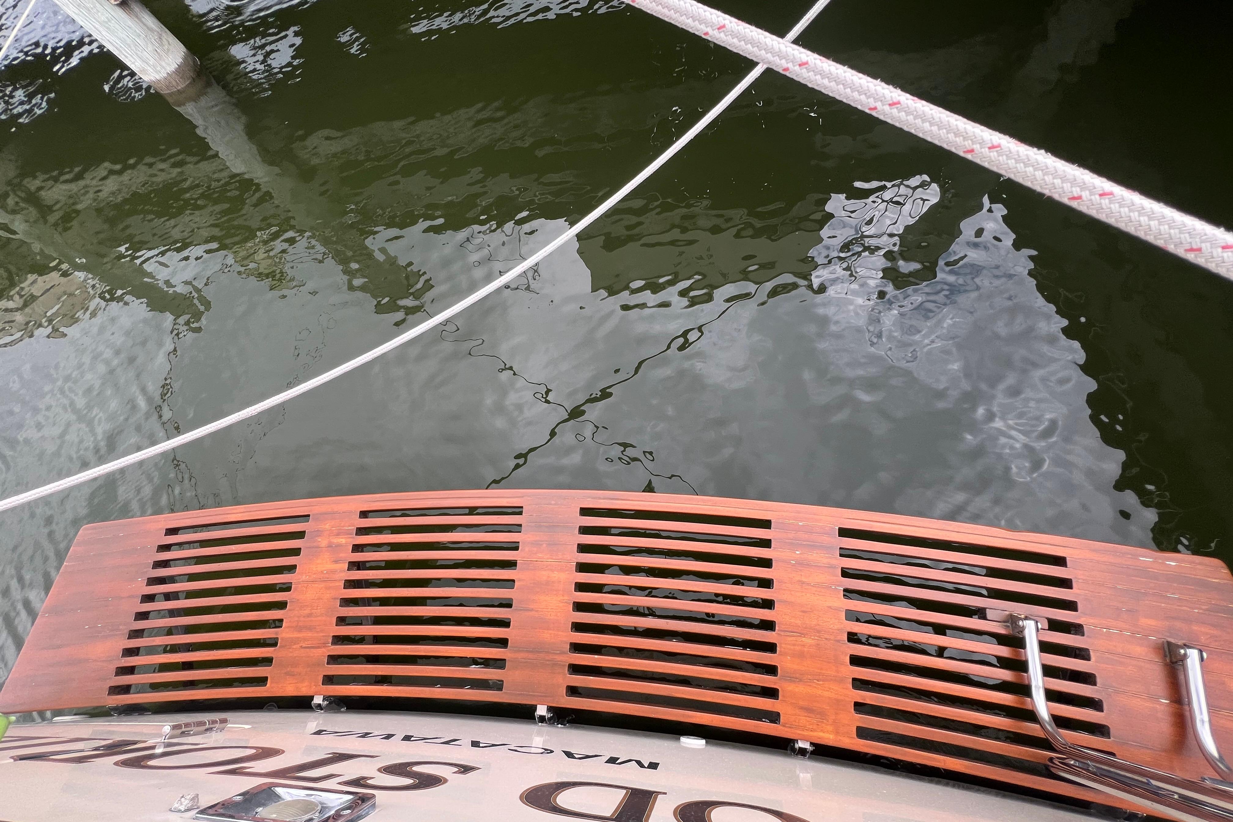 Wooden swim platform on 1985 Tiara 36 OPEN boat, docked with ropes.