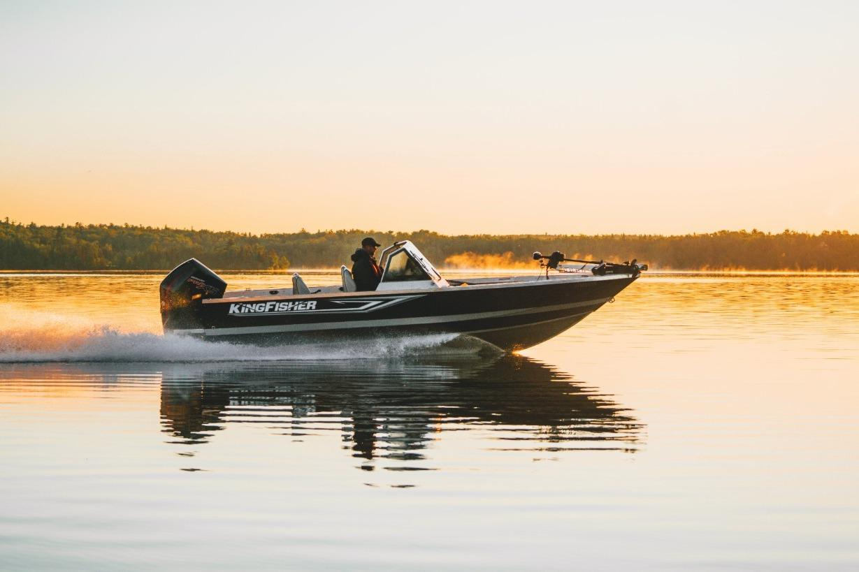 2026 KingFisher 2125 Arrow Sport boat cruising on a serene lake at sunset.