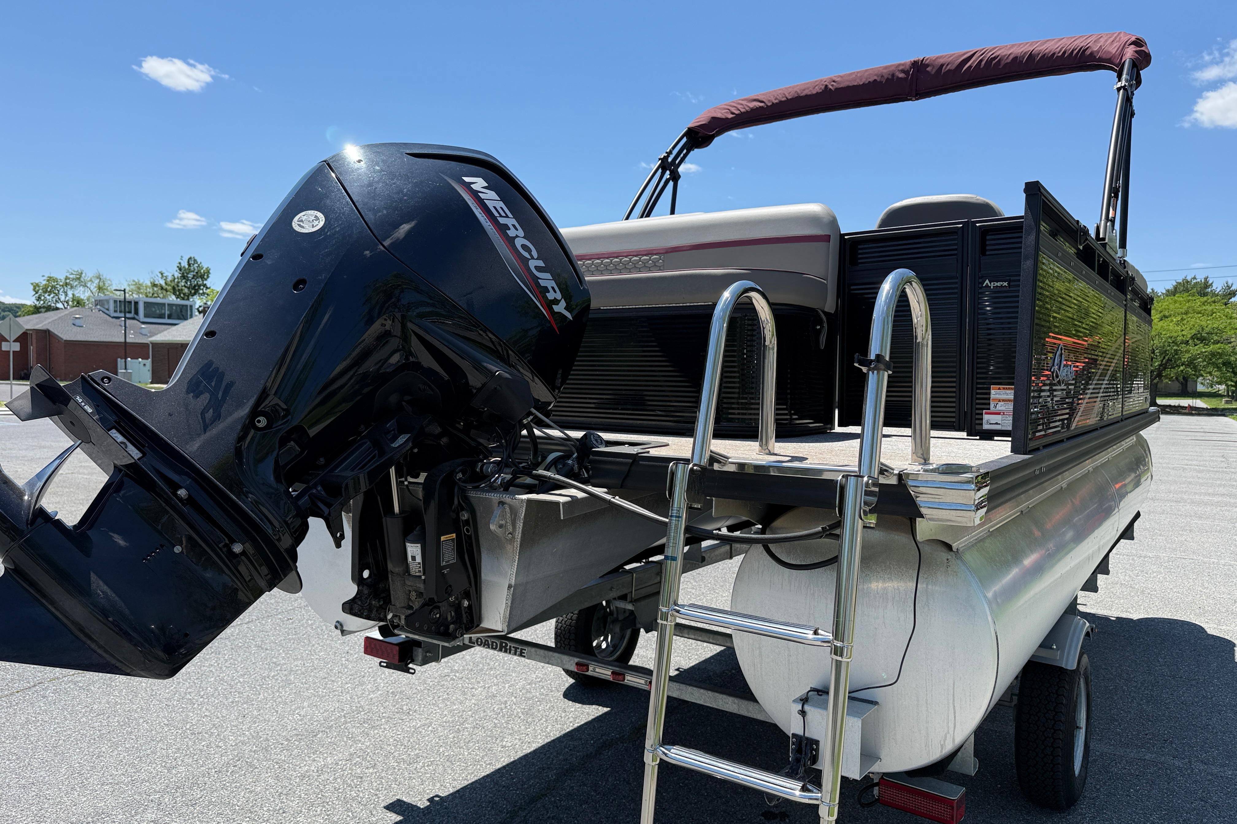 2023 Apex 818 pontoon boat with Mercury outboard motor and ladder, parked outdoors.