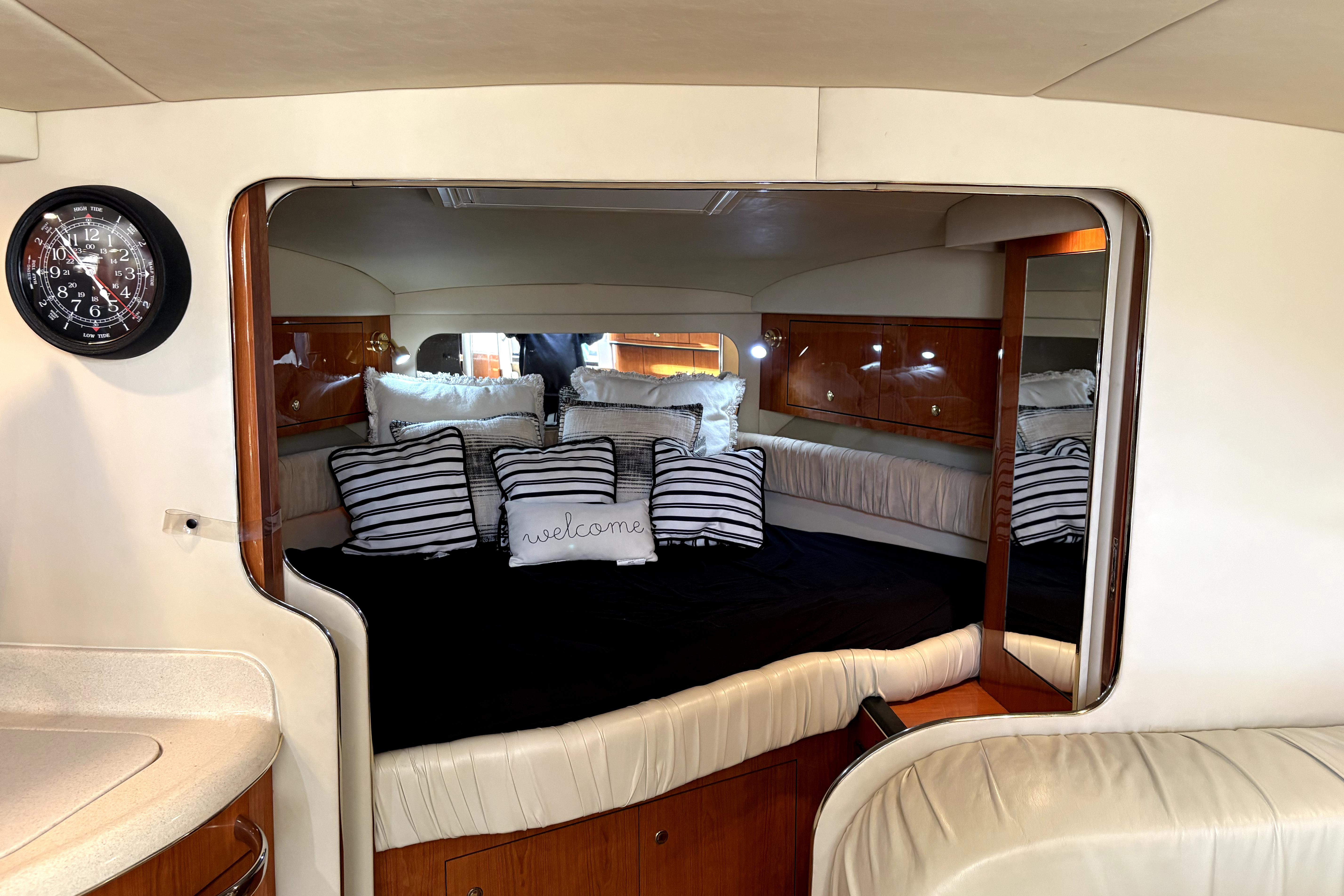 Interior of 2002 Sea Ray 340 Amberjack with cozy bed and striped pillows.