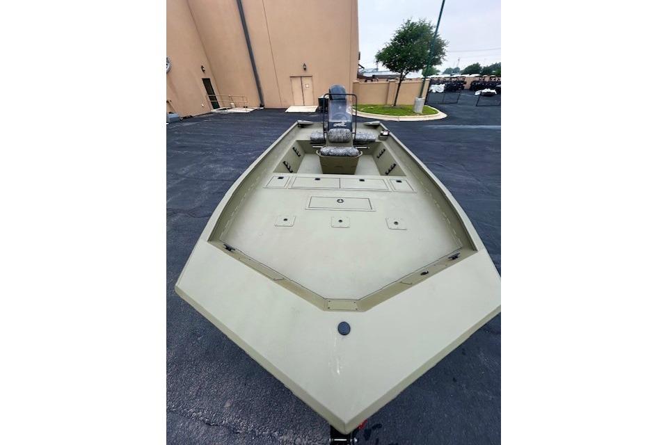 2026 Tracker Grizzly 2072 CC boat, olive green, parked on asphalt near a building.