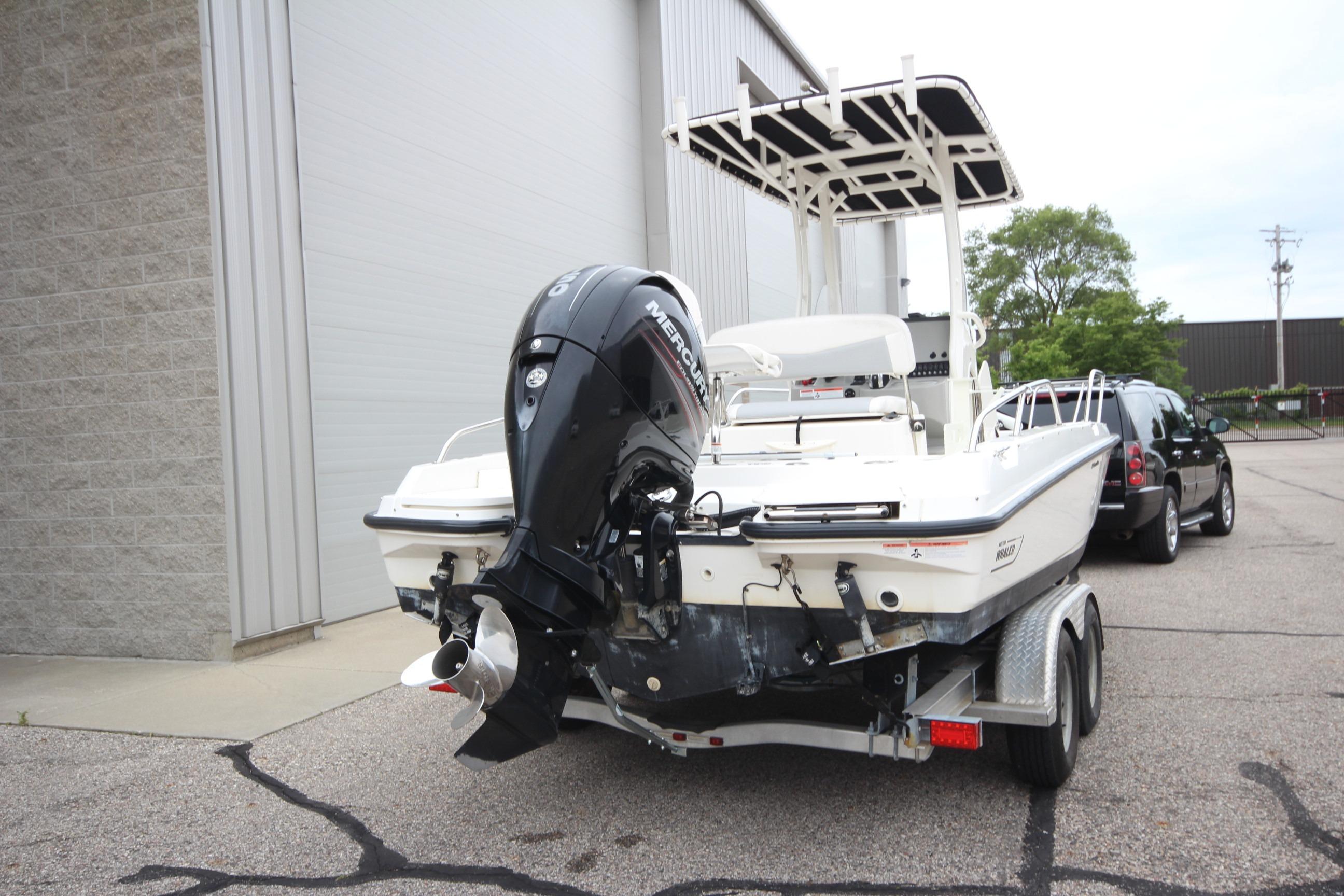 2014 Boston Whaler 210 Dauntless boat on trailer, parked near a building.