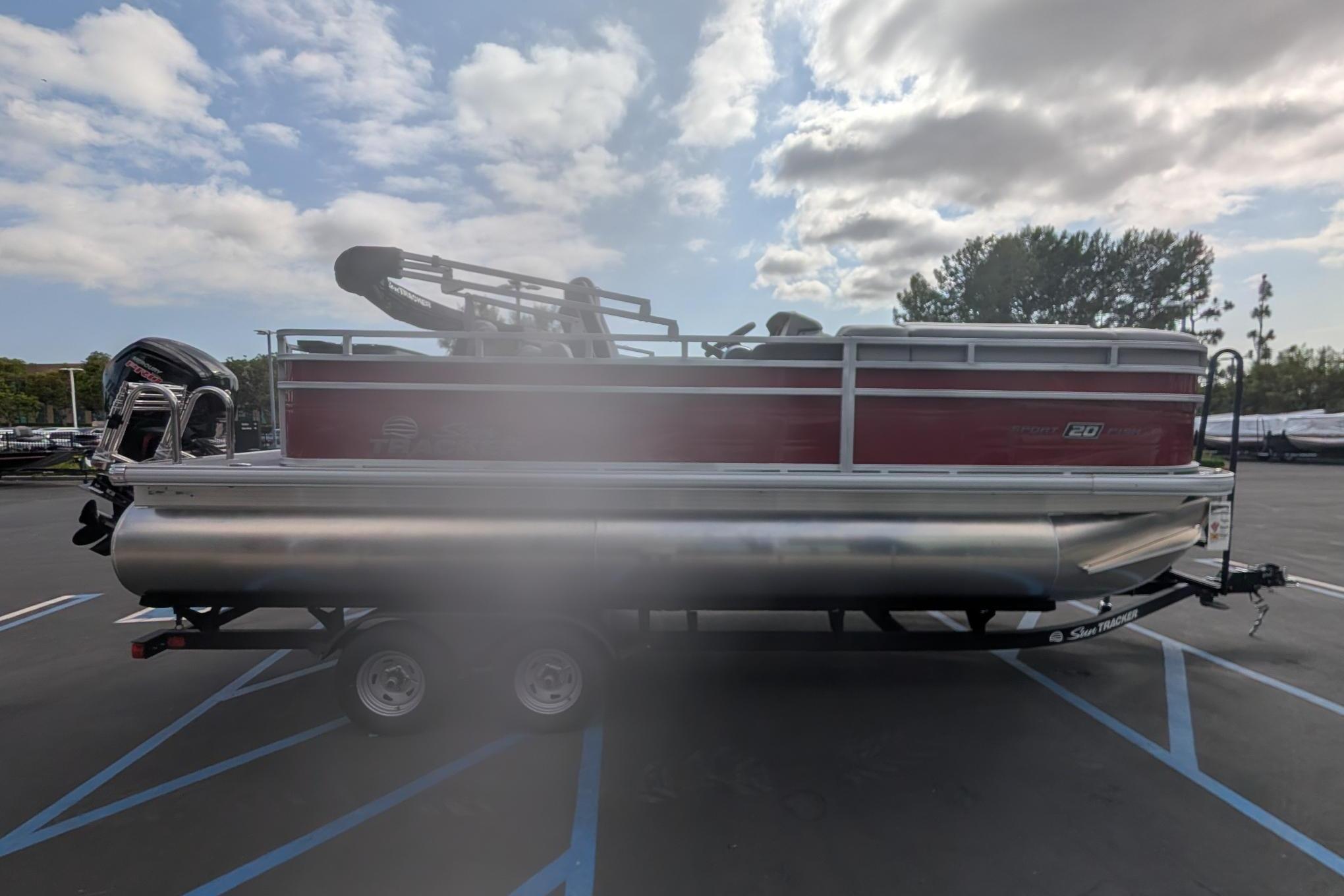 2026 Sun Tracker SportFish 20 DLX pontoon boat on trailer under cloudy sky.