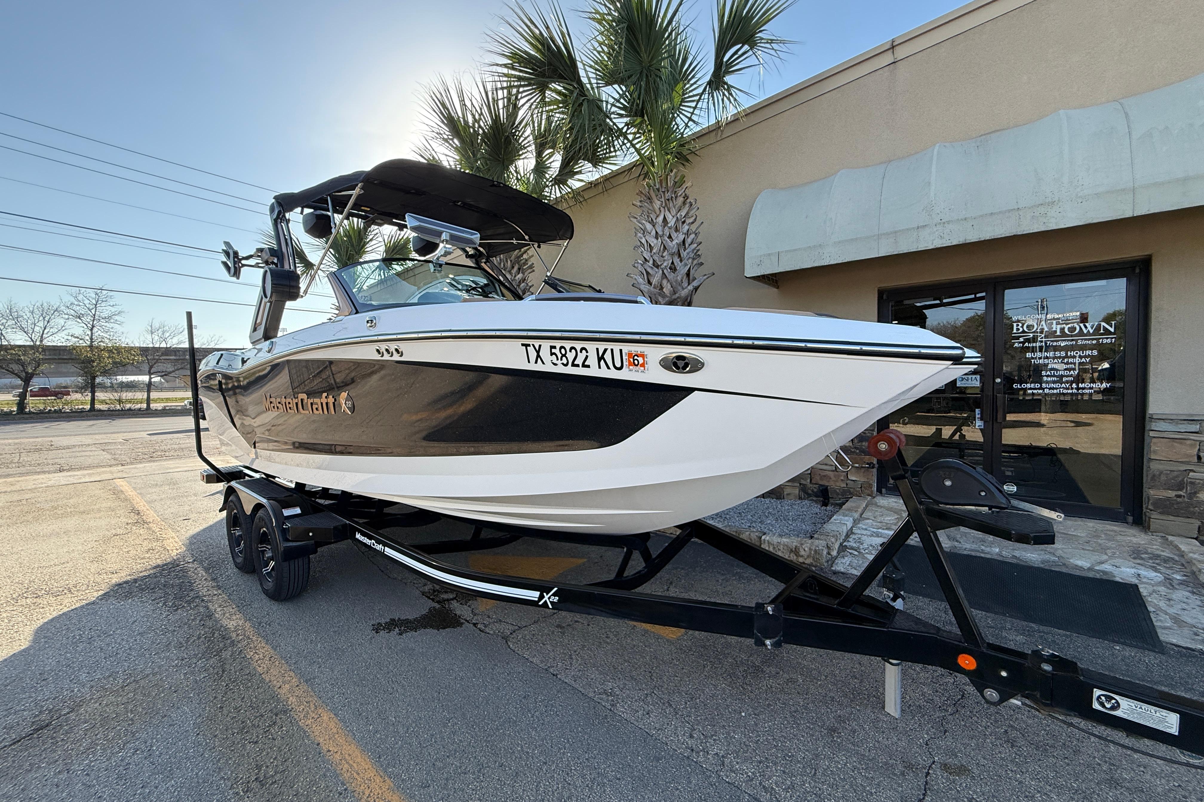 2023 MasterCraft X22 boat on trailer, parked outside a building.