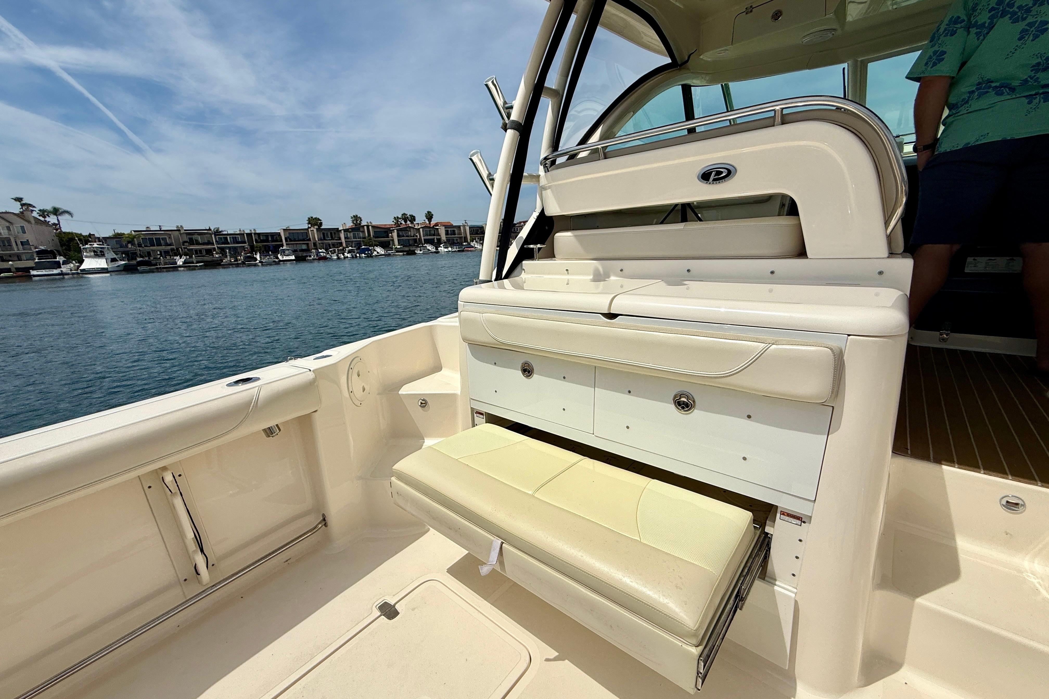 2012 Pursuit OS 345 Offshore boat interior with seating and storage, docked near waterfront homes.