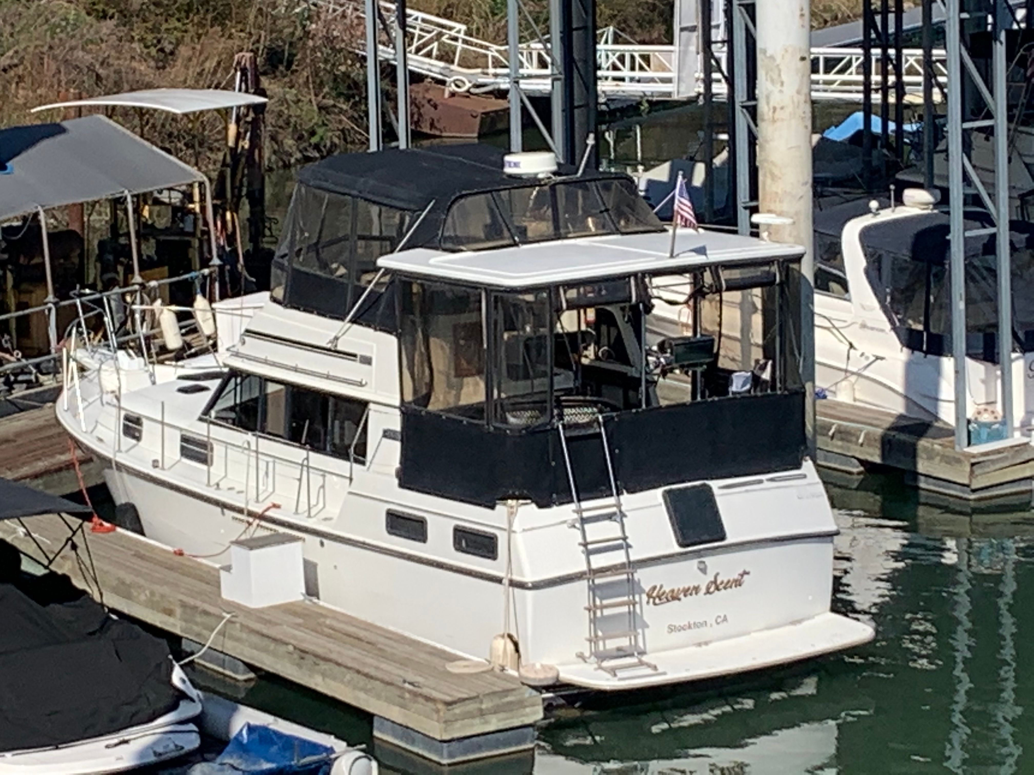 A 1988 Carver 3607 Aft Cabin Motor Yacht docked in a marina. It features a spacious aft deck and ladder.
