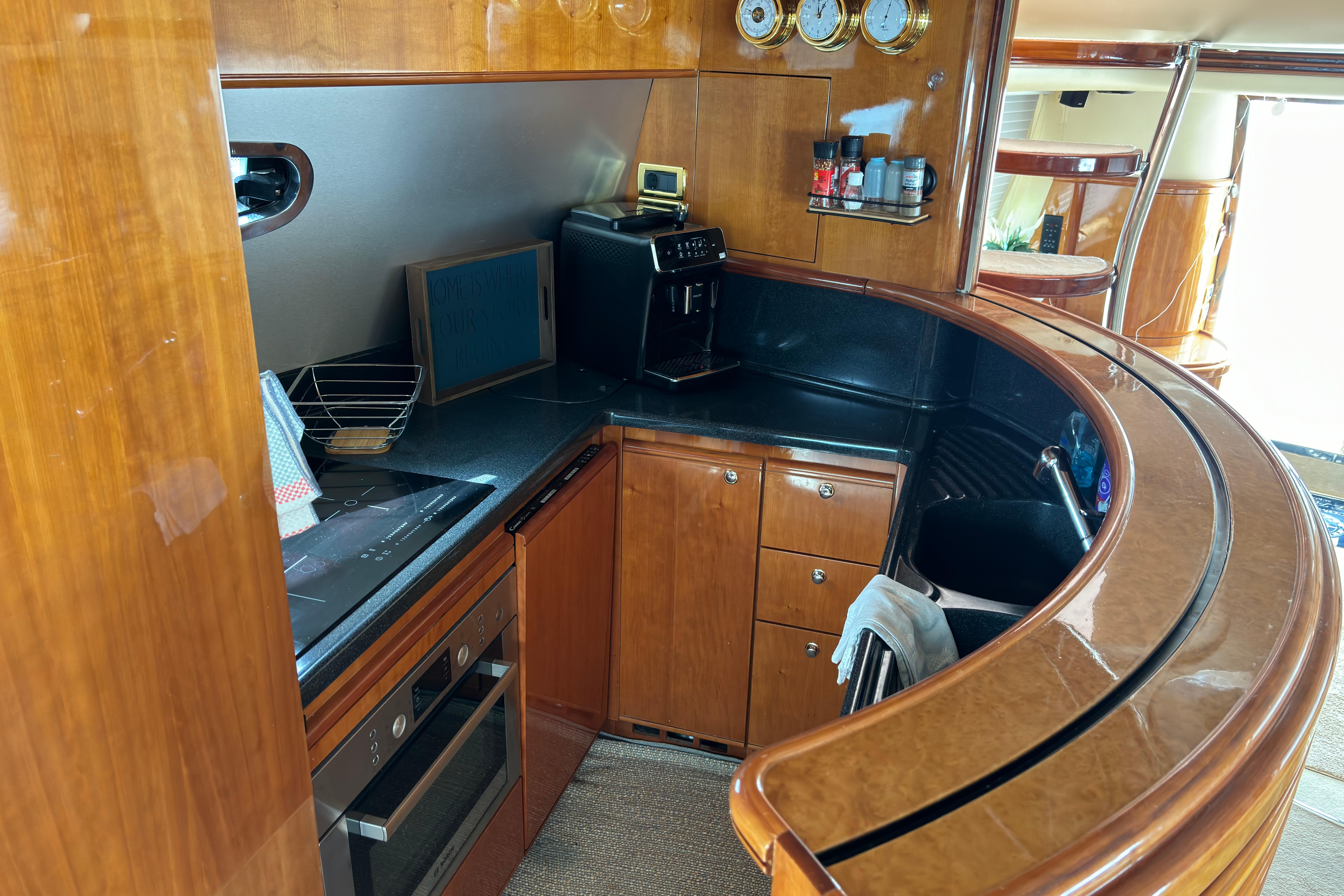 Luxurious kitchen interior of 2002 Azimut 68 Plus yacht with wooden cabinetry and modern appliances.