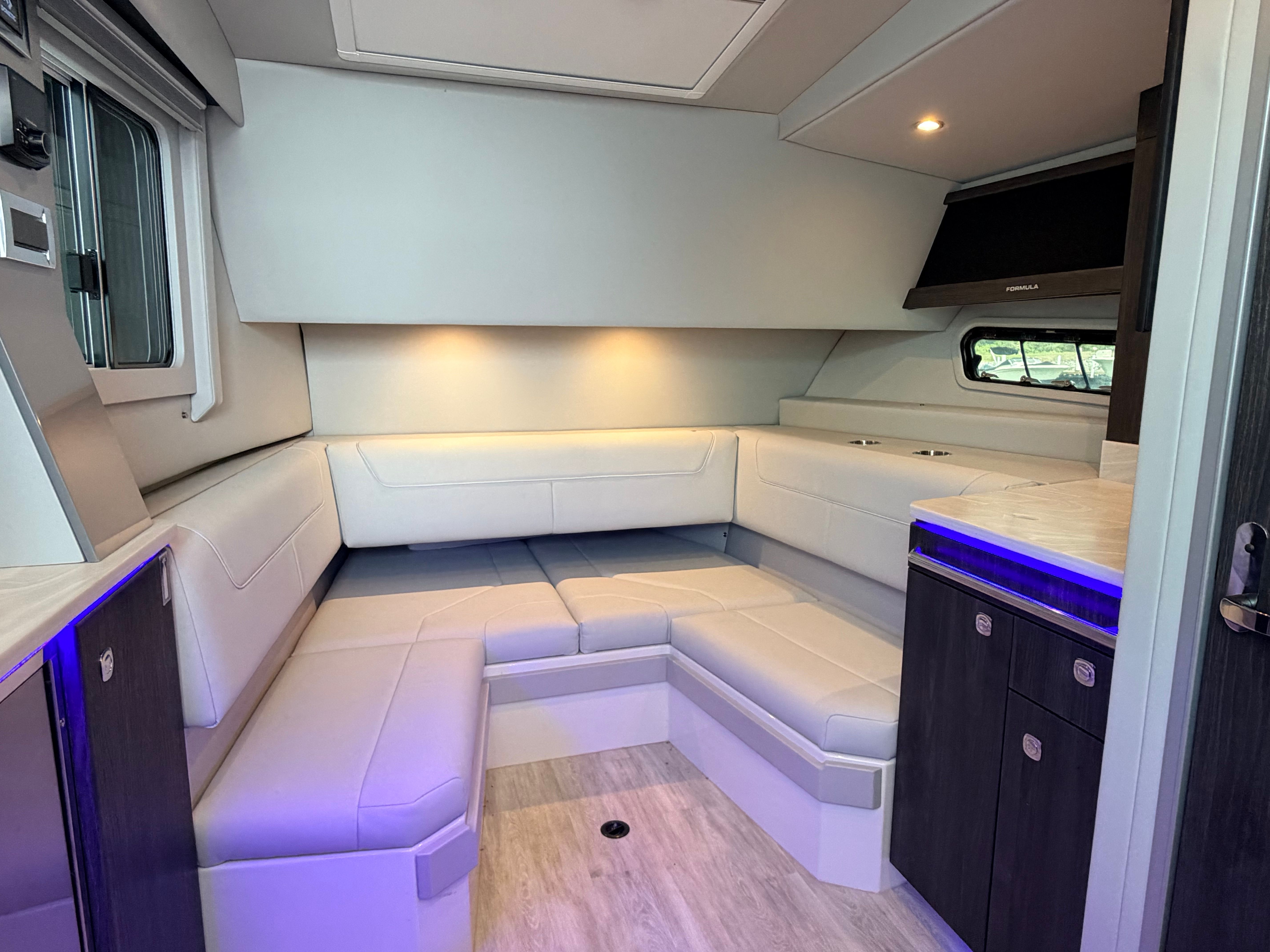 The cabin of the 2023 Formula 400 Super Sport Crossover features a modern, L-shaped seating area with blue lighting.