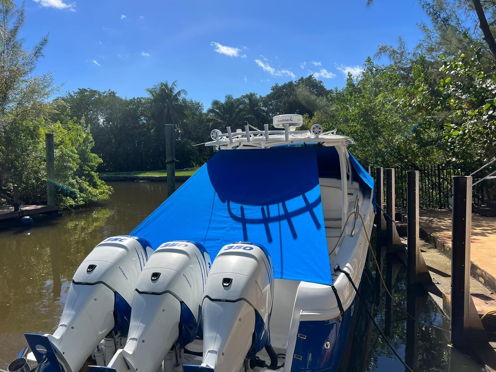 A 2014 Intrepid 375 Walkaround docked at a serene riverside, featuring a blue cover.