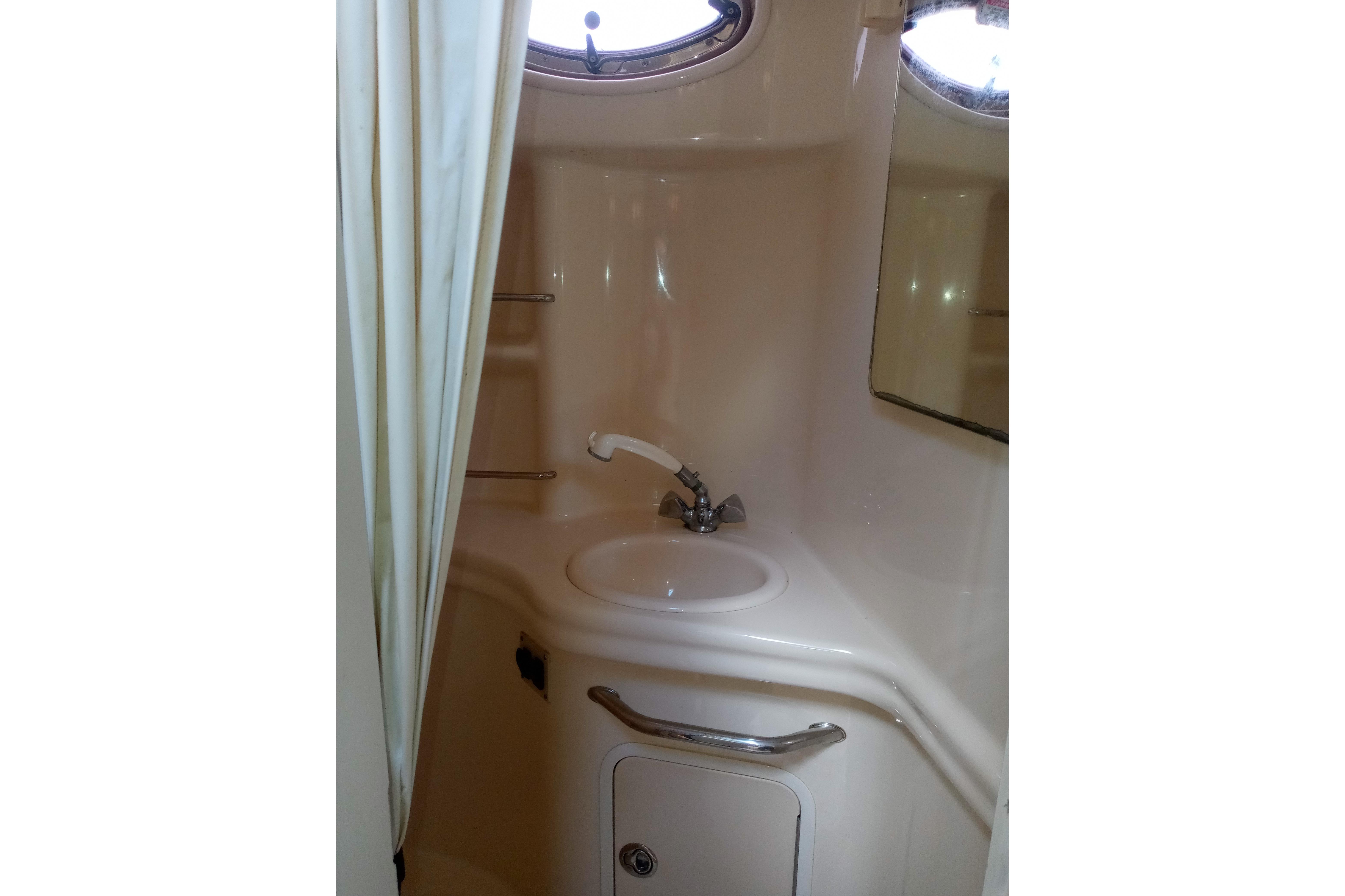 2005 Sea Ray 300 Sundancer bathroom with sink, mirror, and porthole window.