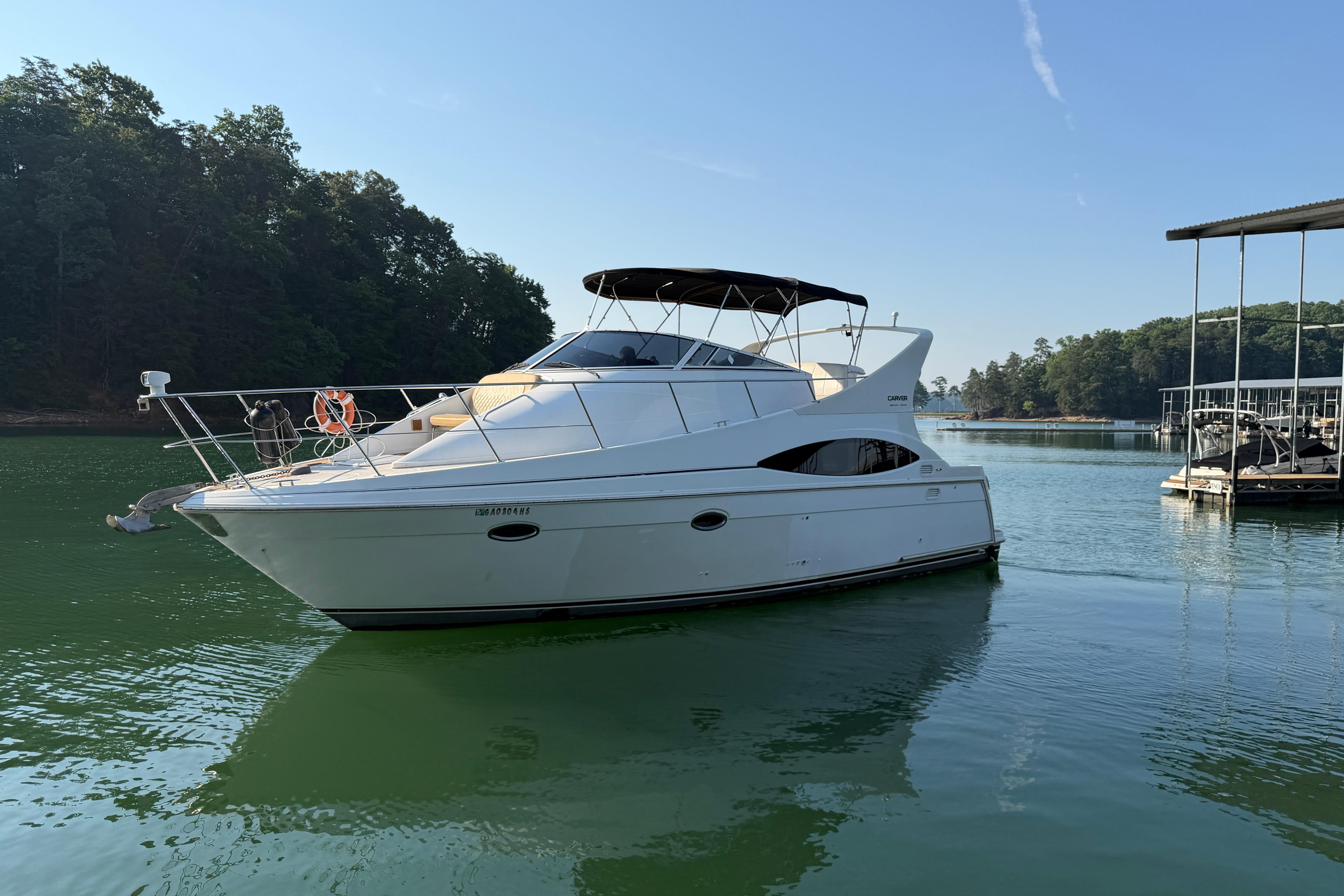 2003 Carver 350 Mariner yacht docked on a serene lake with lush greenery.