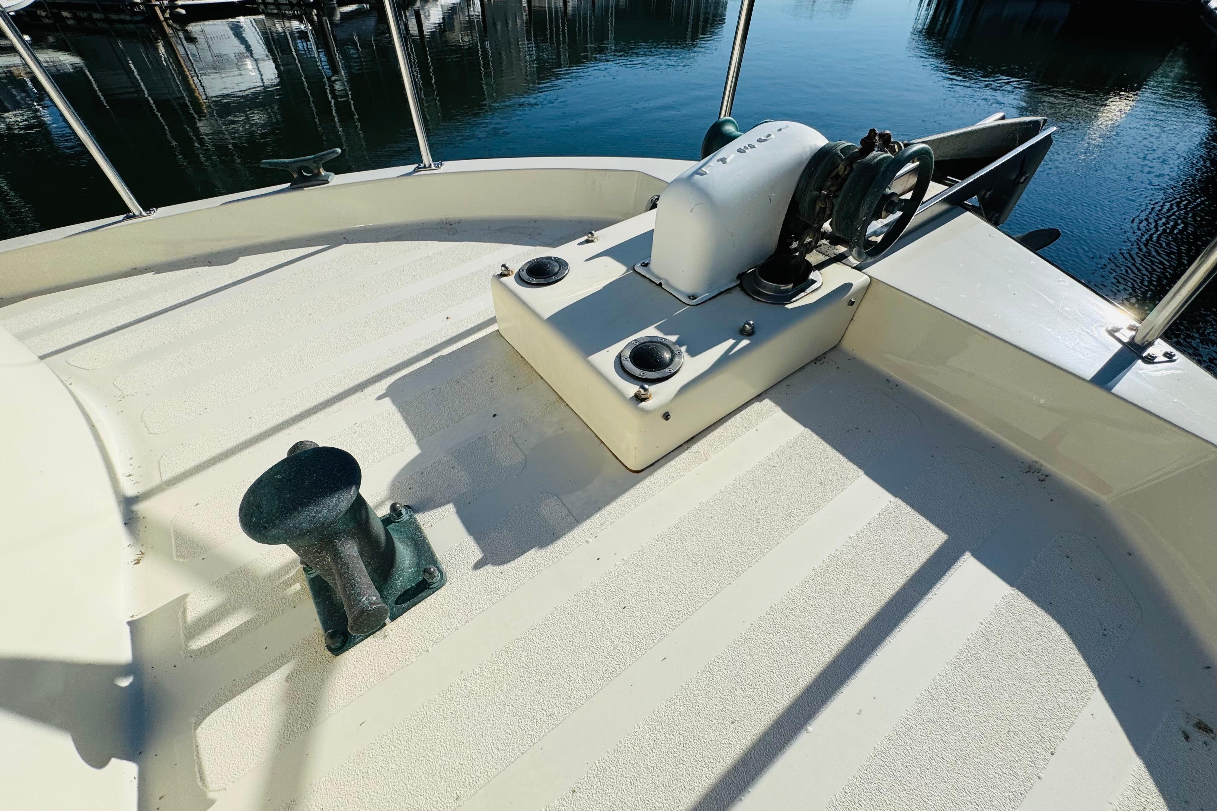 Nordic Tug 32 (1996) bow deck with anchor winch and cleat, docked in marina.