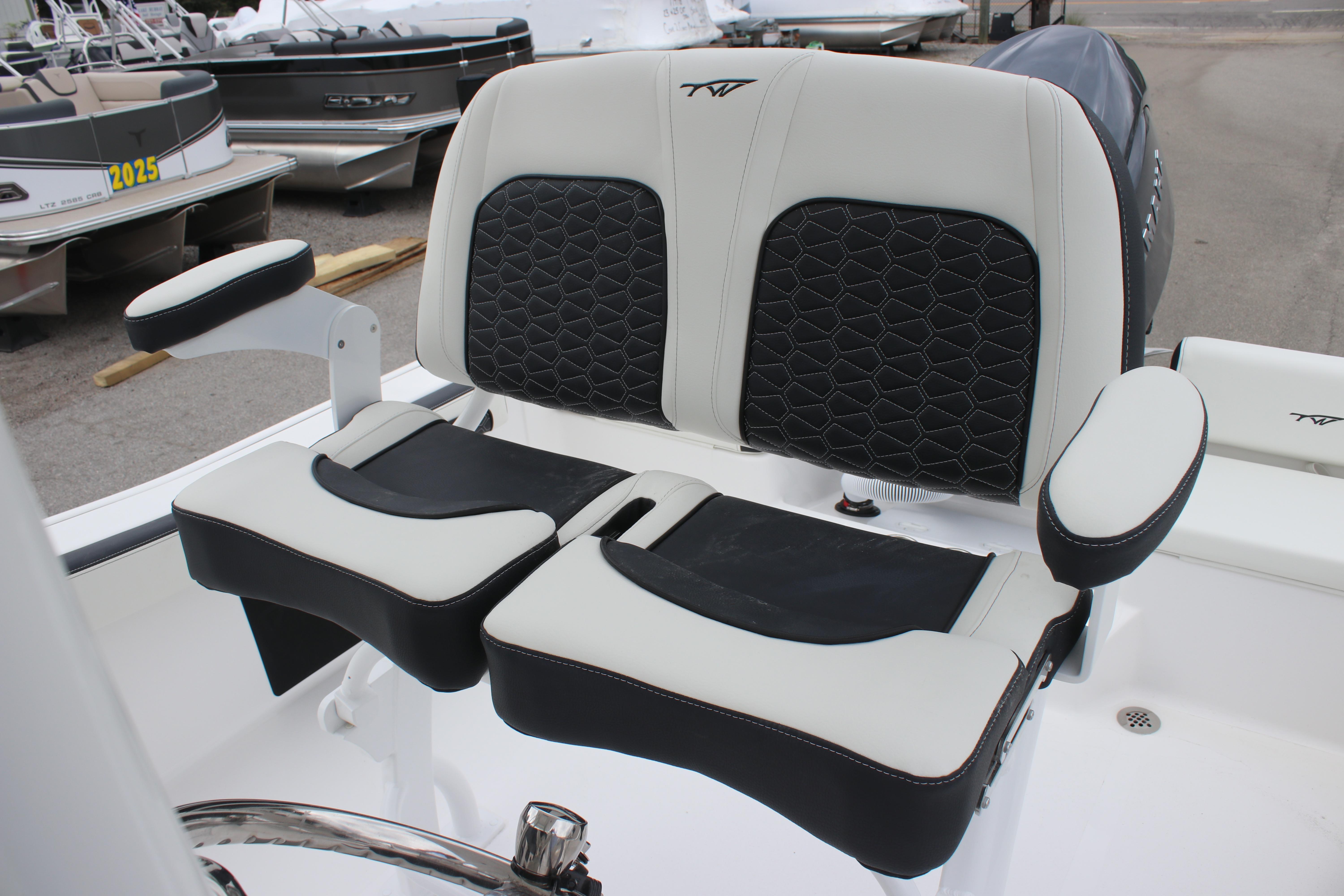 2026 Tidewater 198 CC Adventure boat seats with black and white upholstery, docked near other boats.