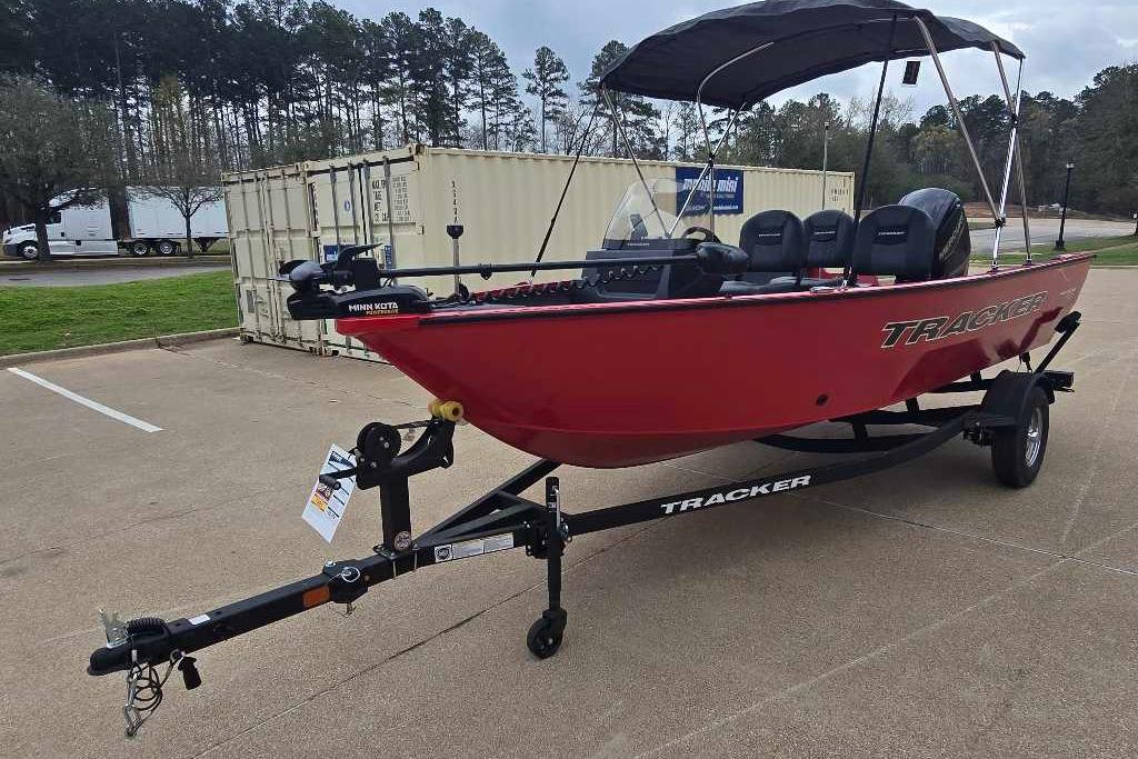 2026 Tracker Pro Guide V-16 SC boat in red on a trailer, parked outdoors.