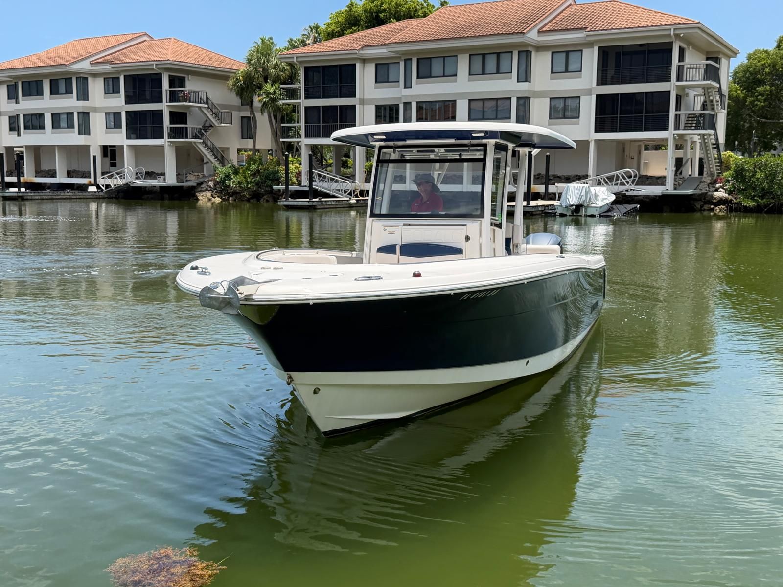 2017 Robalo R302 Center Console boat on calm water near buildings.