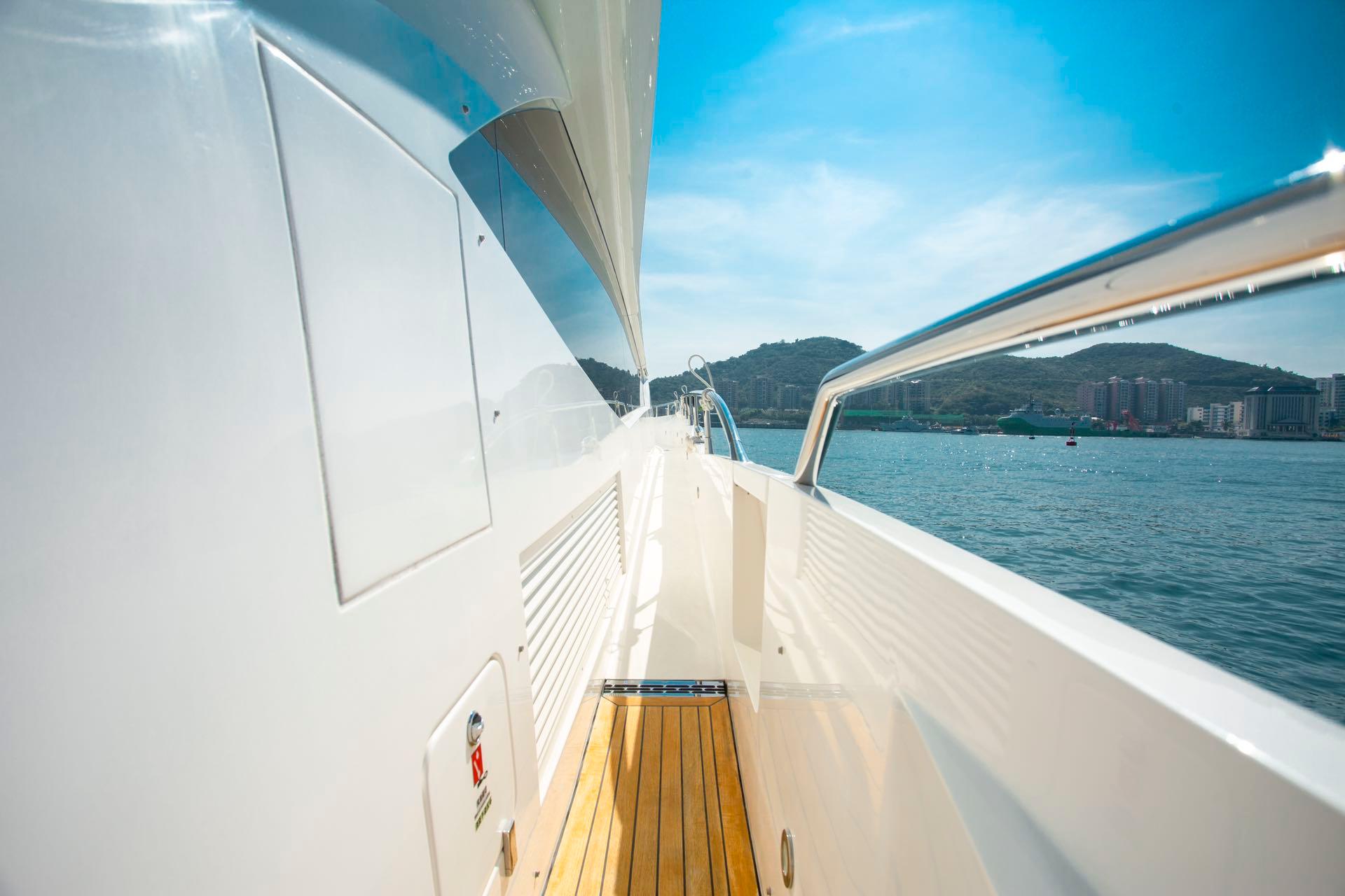 Side view of a 2016 Sunseeker 75 Yacht on a sunny day, overlooking the sea.