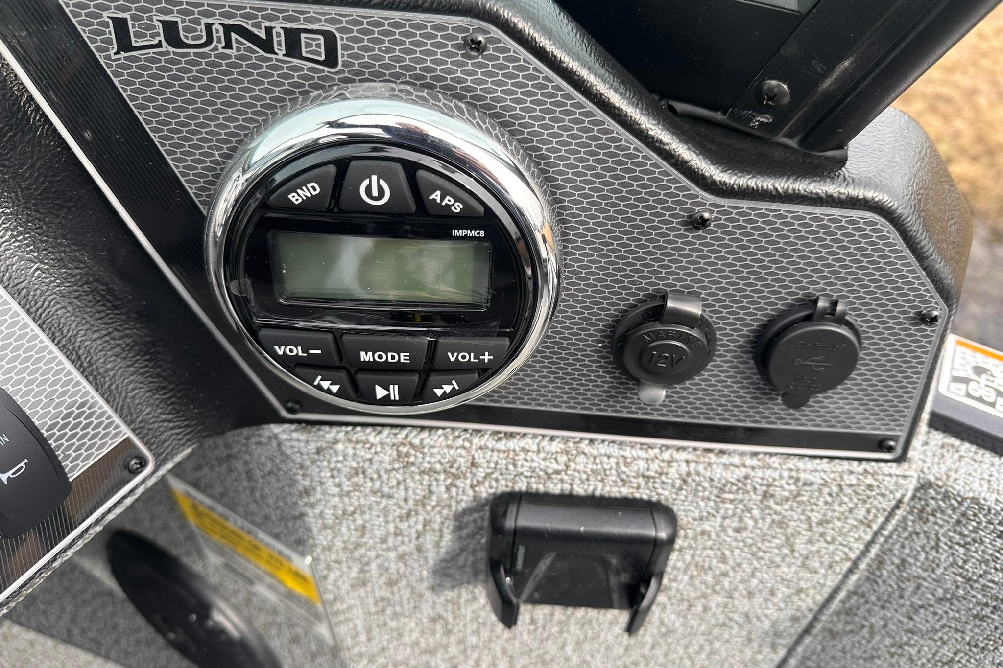 Control panel of 2026 Lund 1775 Adventure Sport boat with audio system and power outlets.