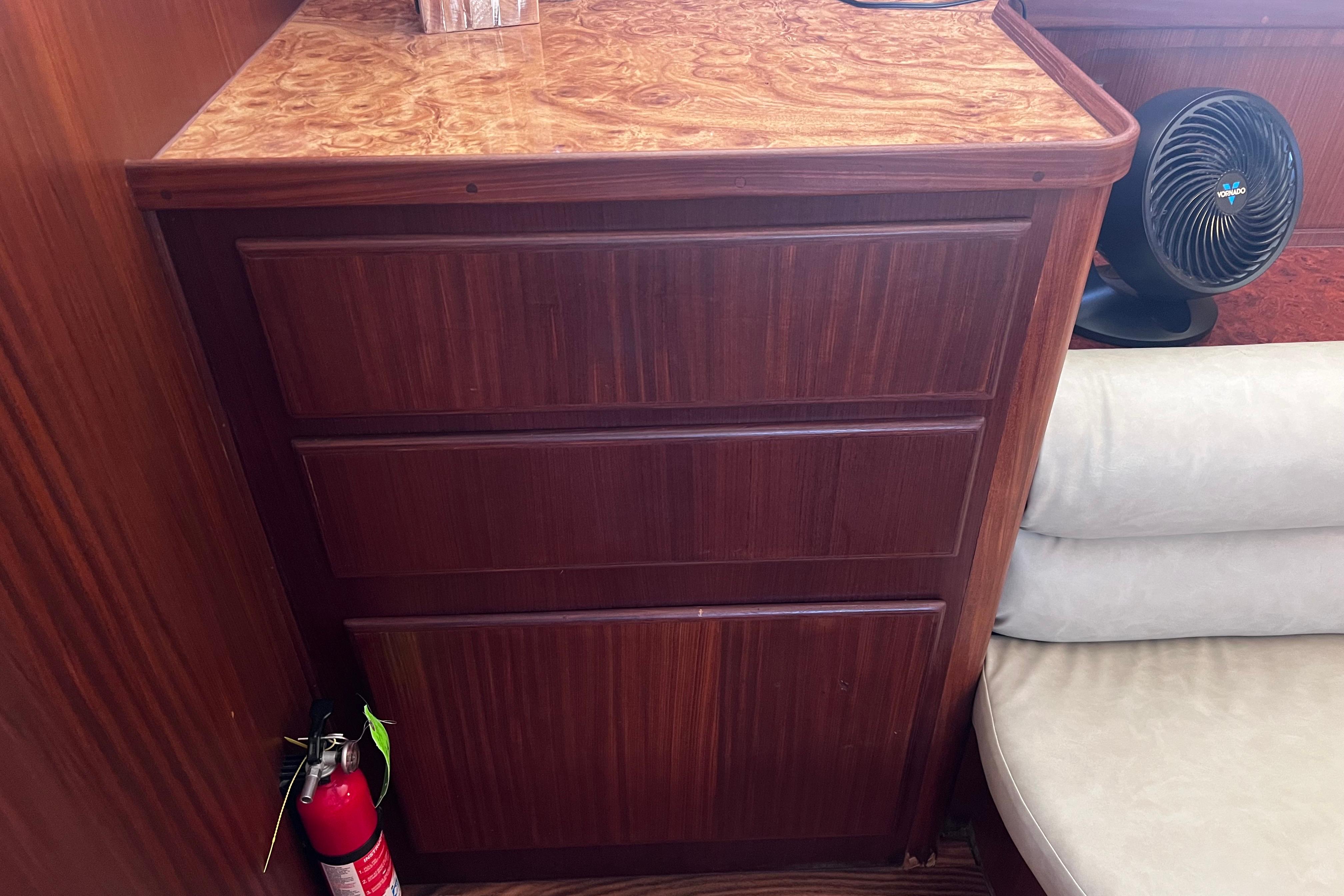 Wooden cabinet with fire extinguisher and fan on a 1987 Hatteras 70 Cockpit Motor Yacht.