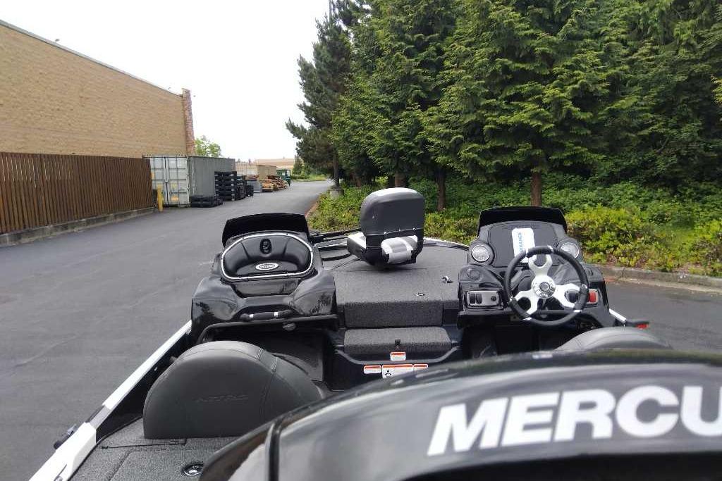 2026 Nitro Z17 boat with steering wheel and controls, parked near trees and industrial area.