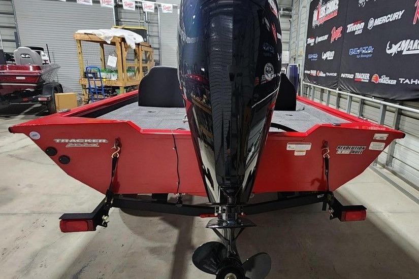 2026 Tracker Pro Team 175 boat, red exterior, displayed indoors with motor attached.