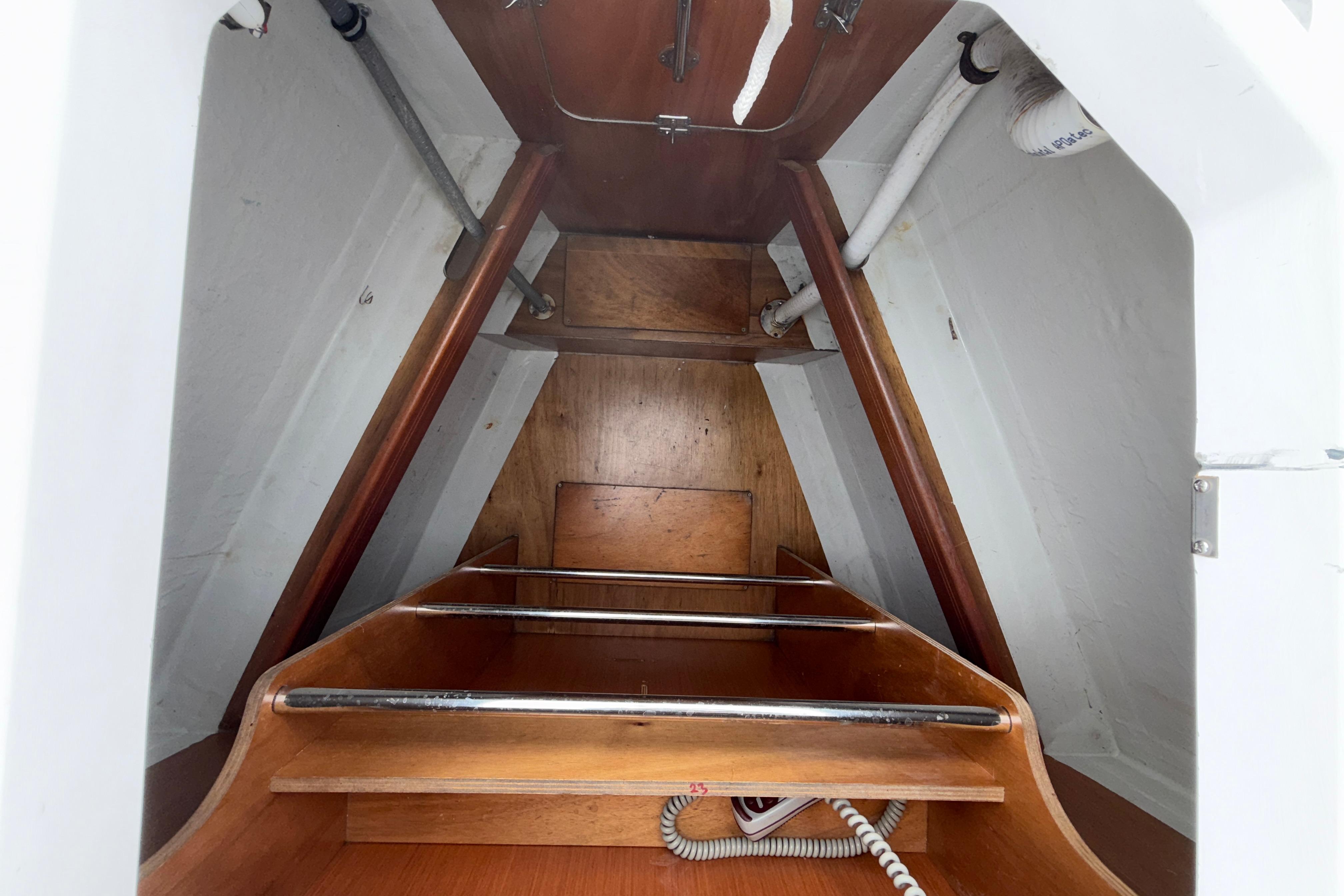 Interior of 2018 Bavaria 46 sailboat showing wooden storage compartment and pipes.