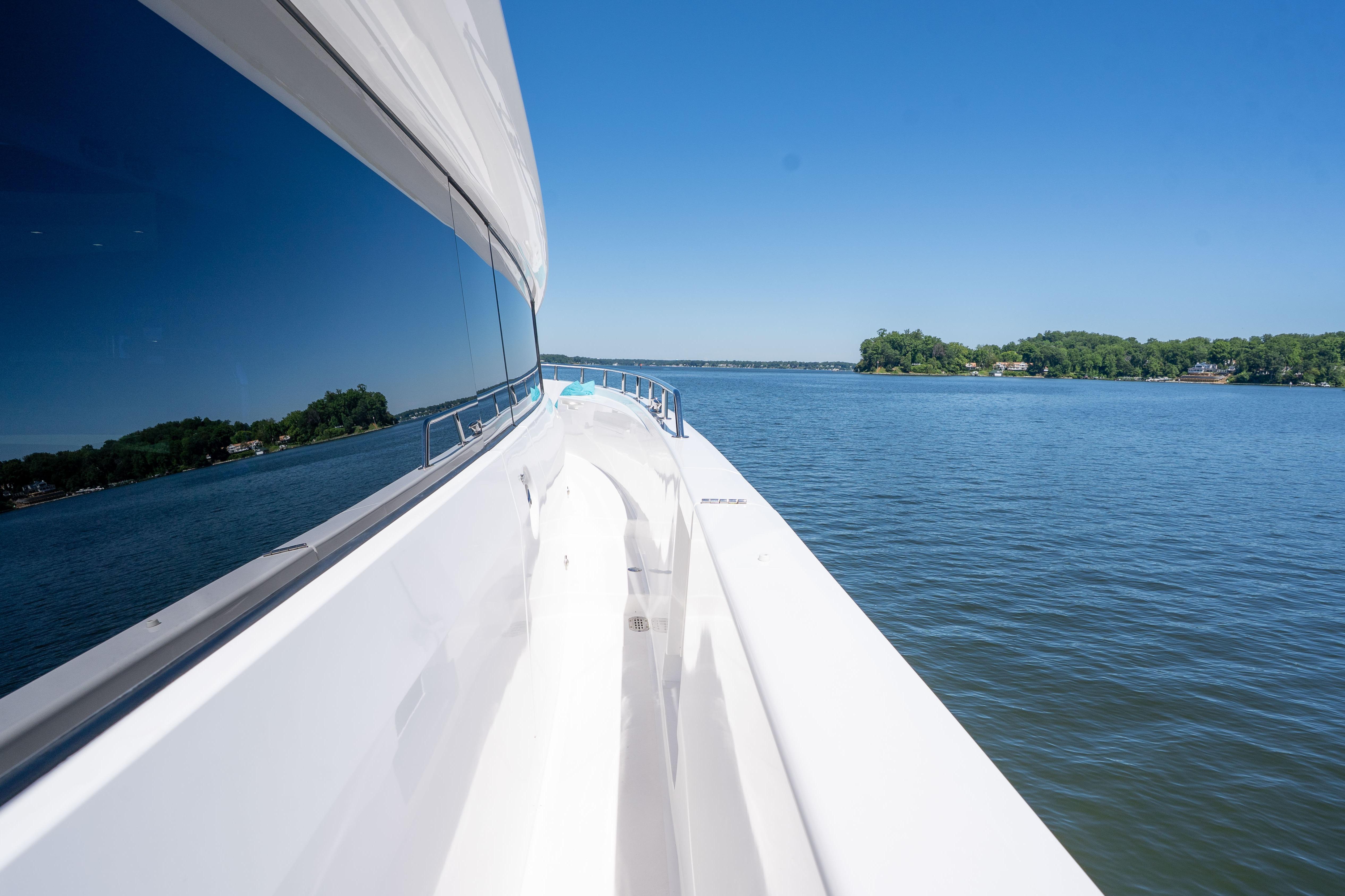 2021 Hatteras M75 Panacera yacht cruising on a serene lake under clear blue skies.