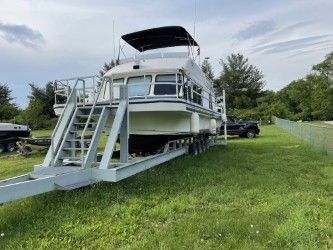 A 1993 Gibson Sport Series houseboat on a trailer in a grassy area.