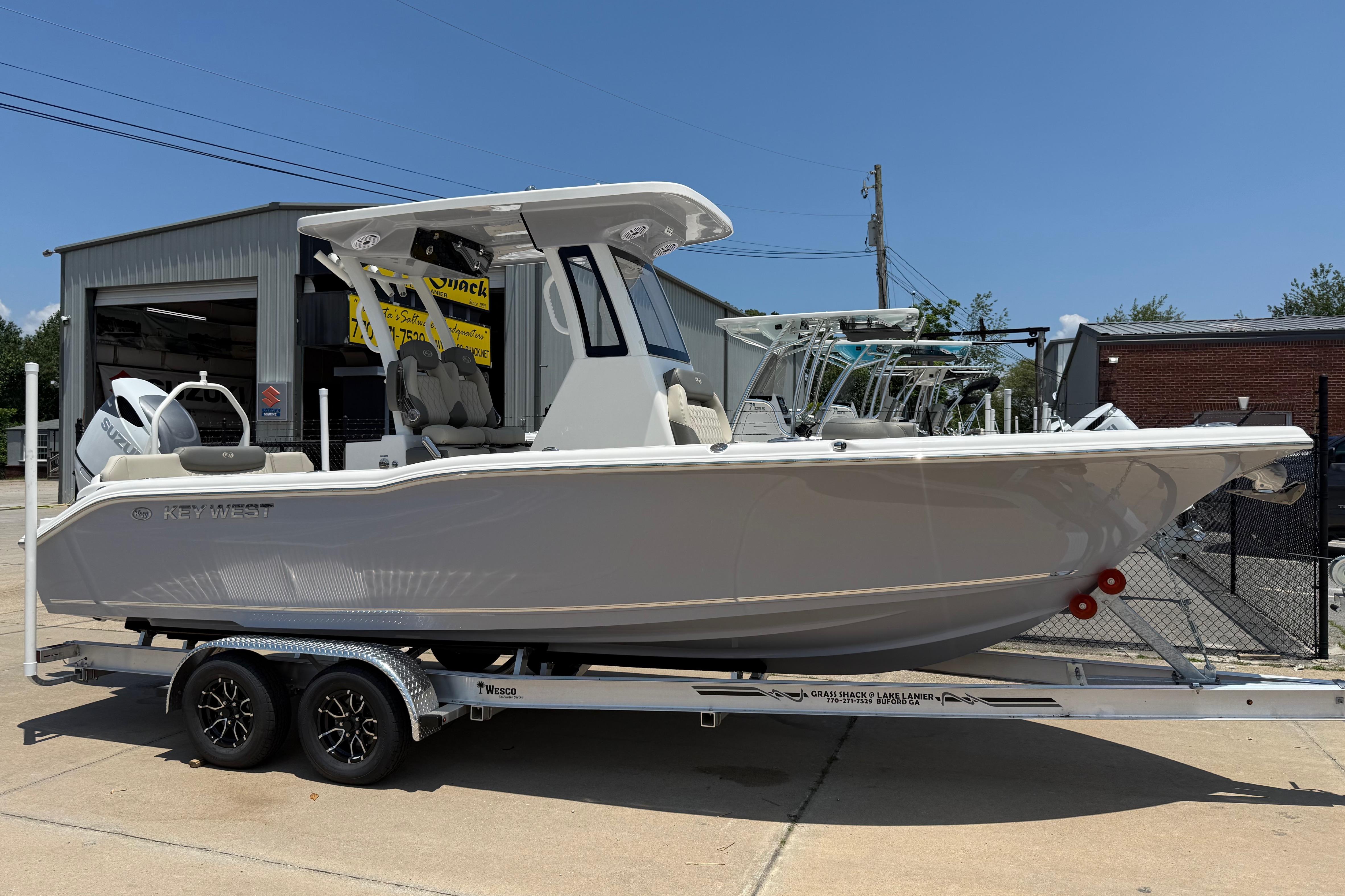 2027 Key West 249 FS boat on trailer, parked outside a garage under clear blue sky.