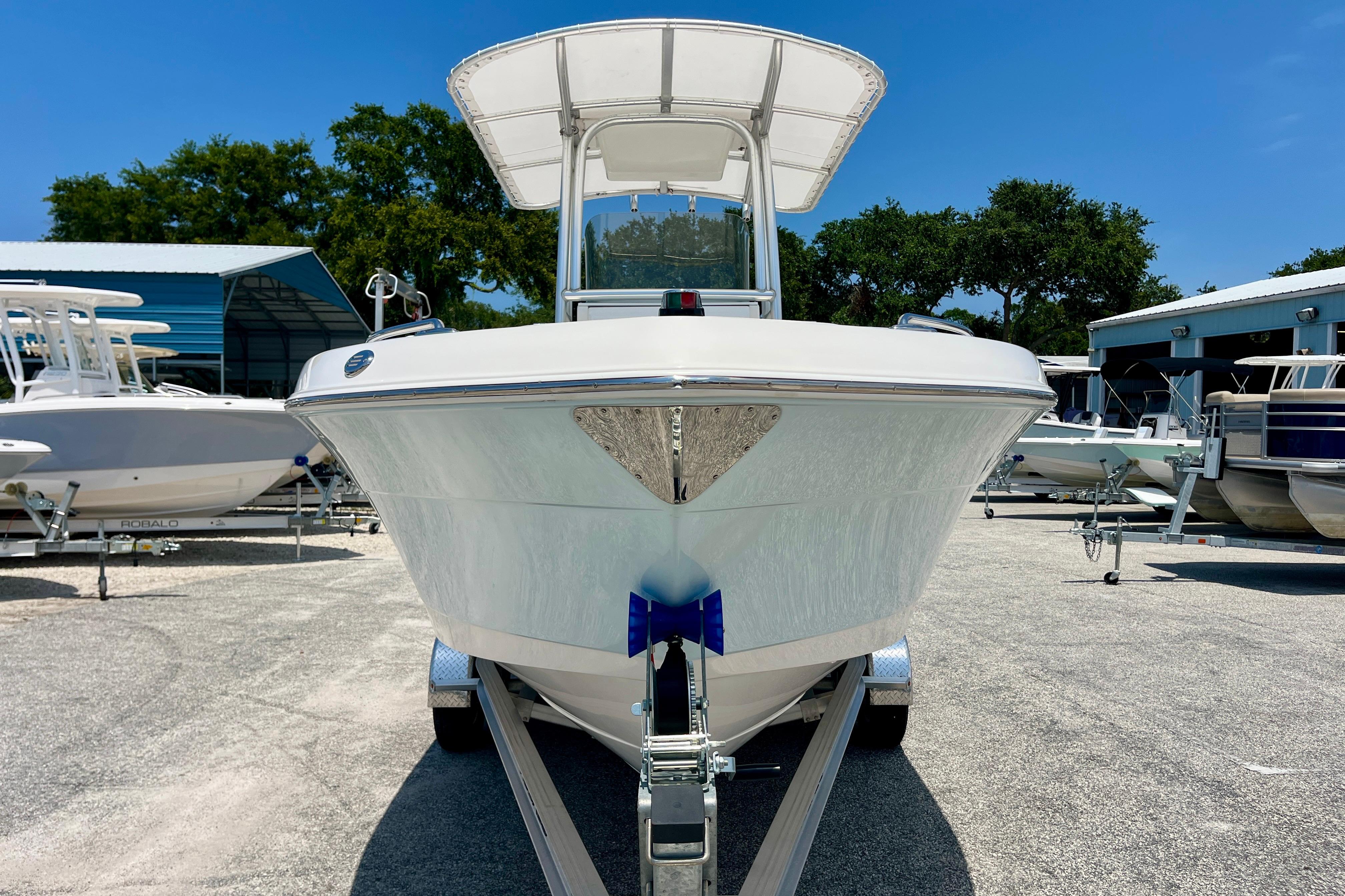 2016 Robalo R222 Center Console boat on trailer, parked outdoors under clear blue sky.