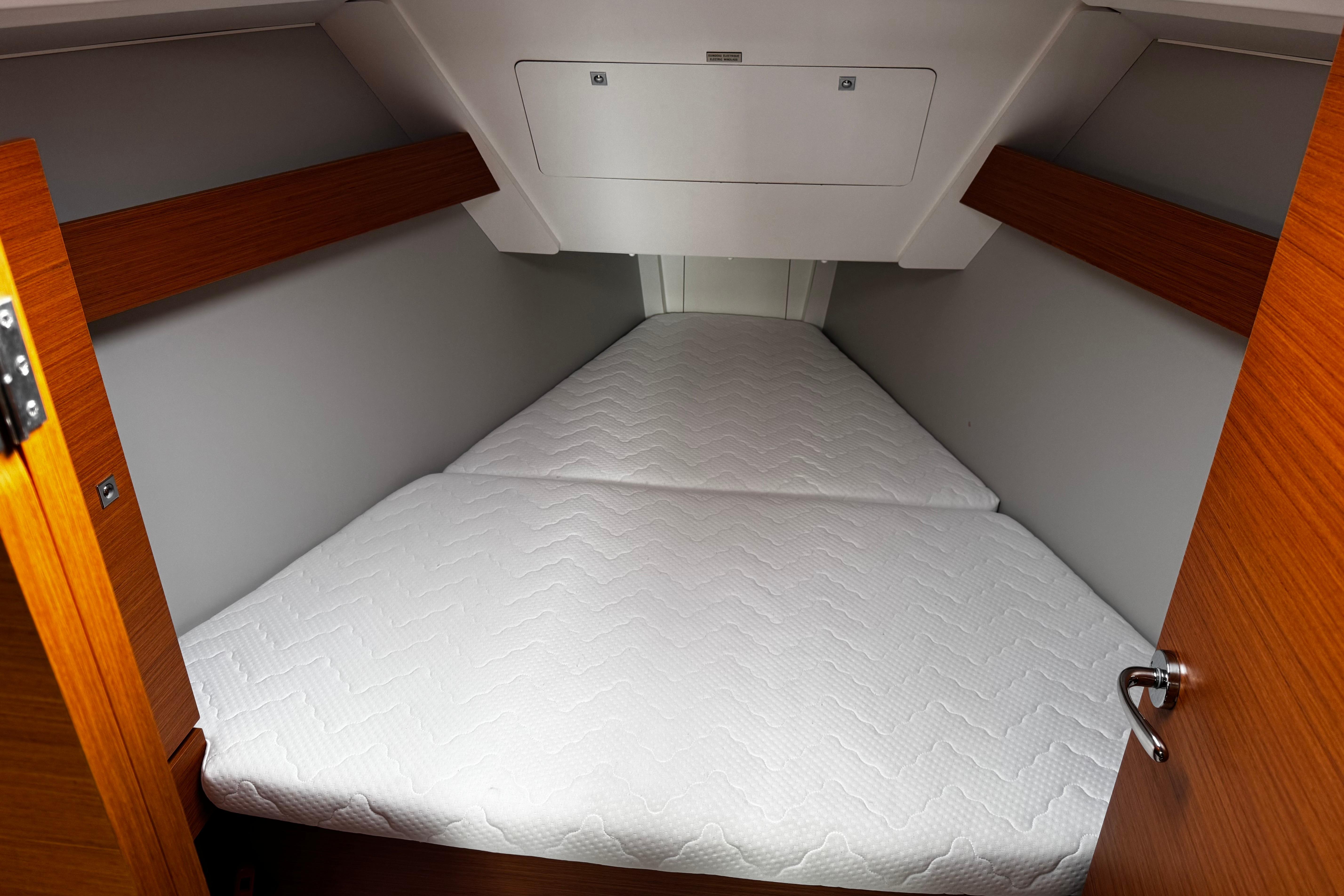 2022 Dufour 32 yacht cabin with white mattress and wooden accents.
