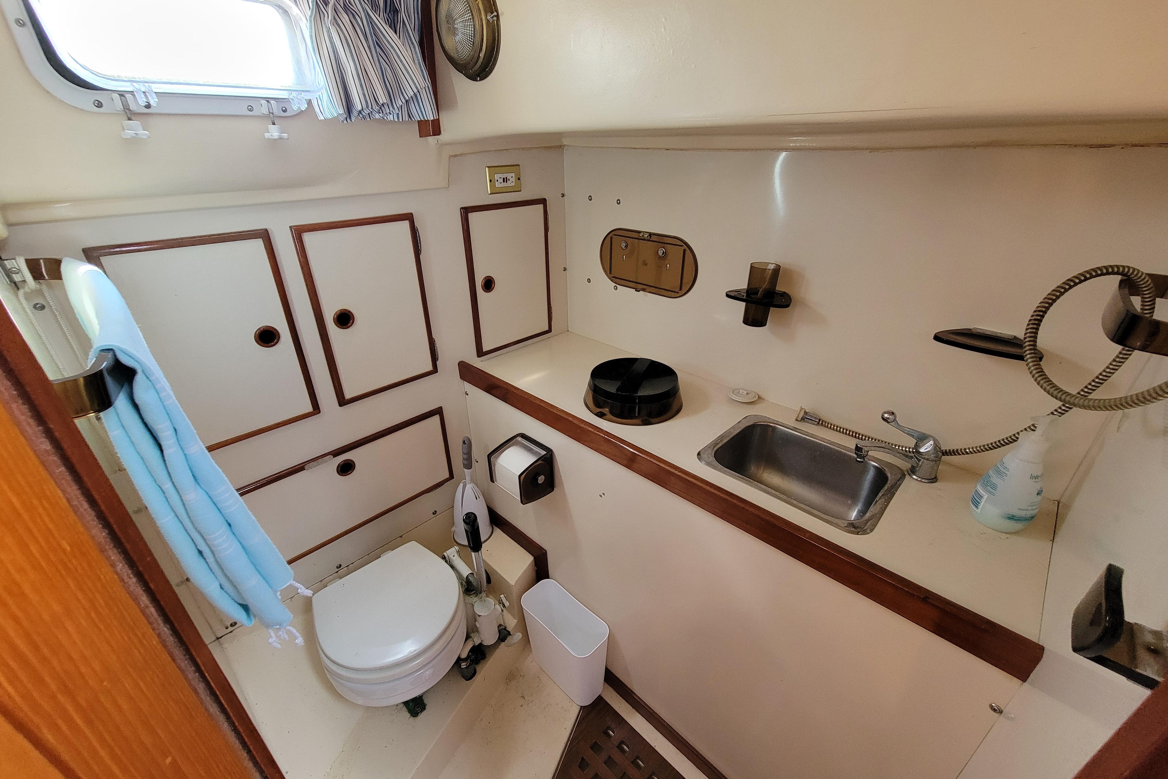 1979 Whitby 42 yacht bathroom with sink, toilet, storage cabinets, and nautical decor.
