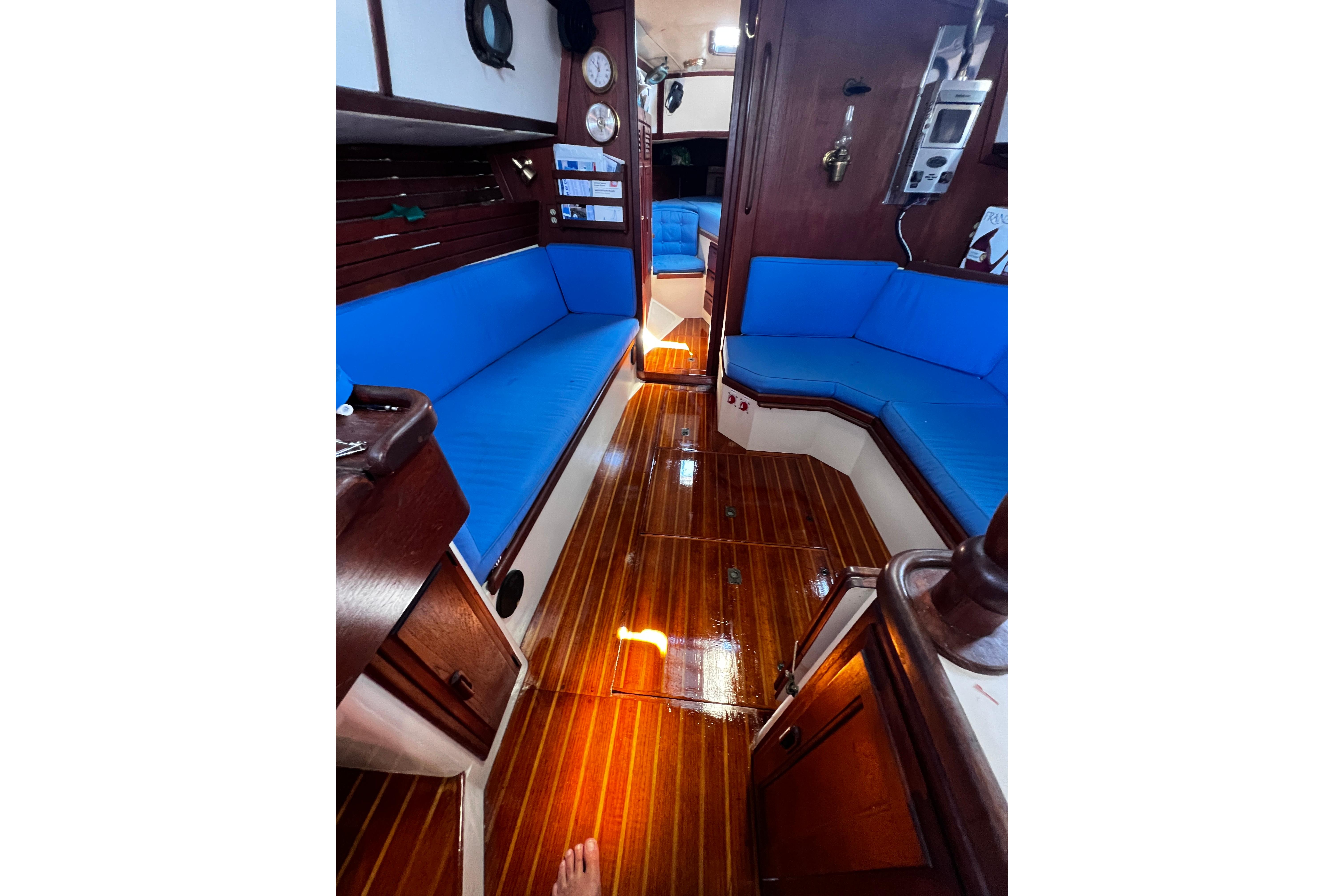 Interior of 1982 Pacific Seacraft 37 sailboat with polished wood and blue seating.