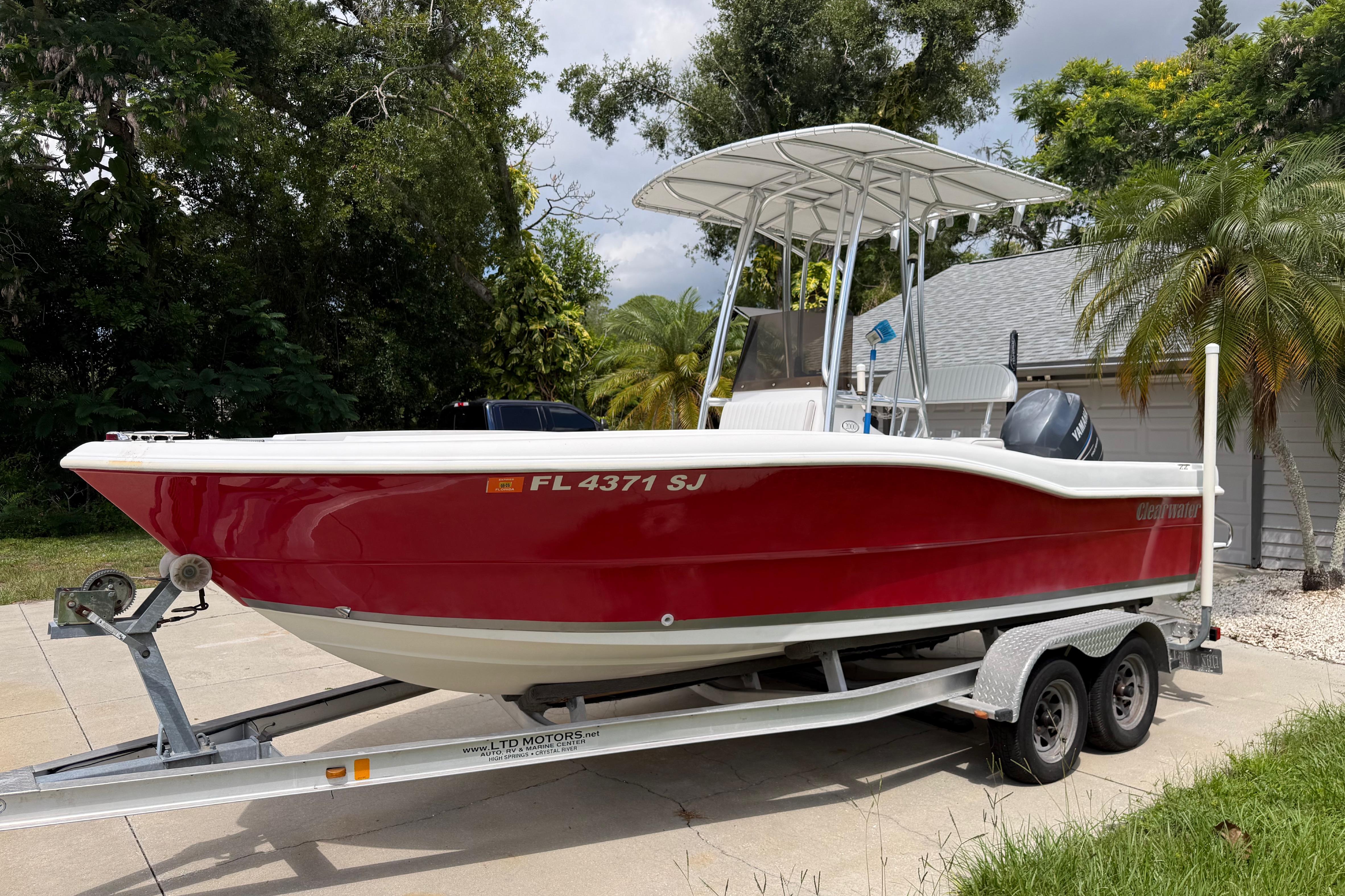 Red 2012 Clearwater 2000 Center Console boat on trailer, parked outdoors.