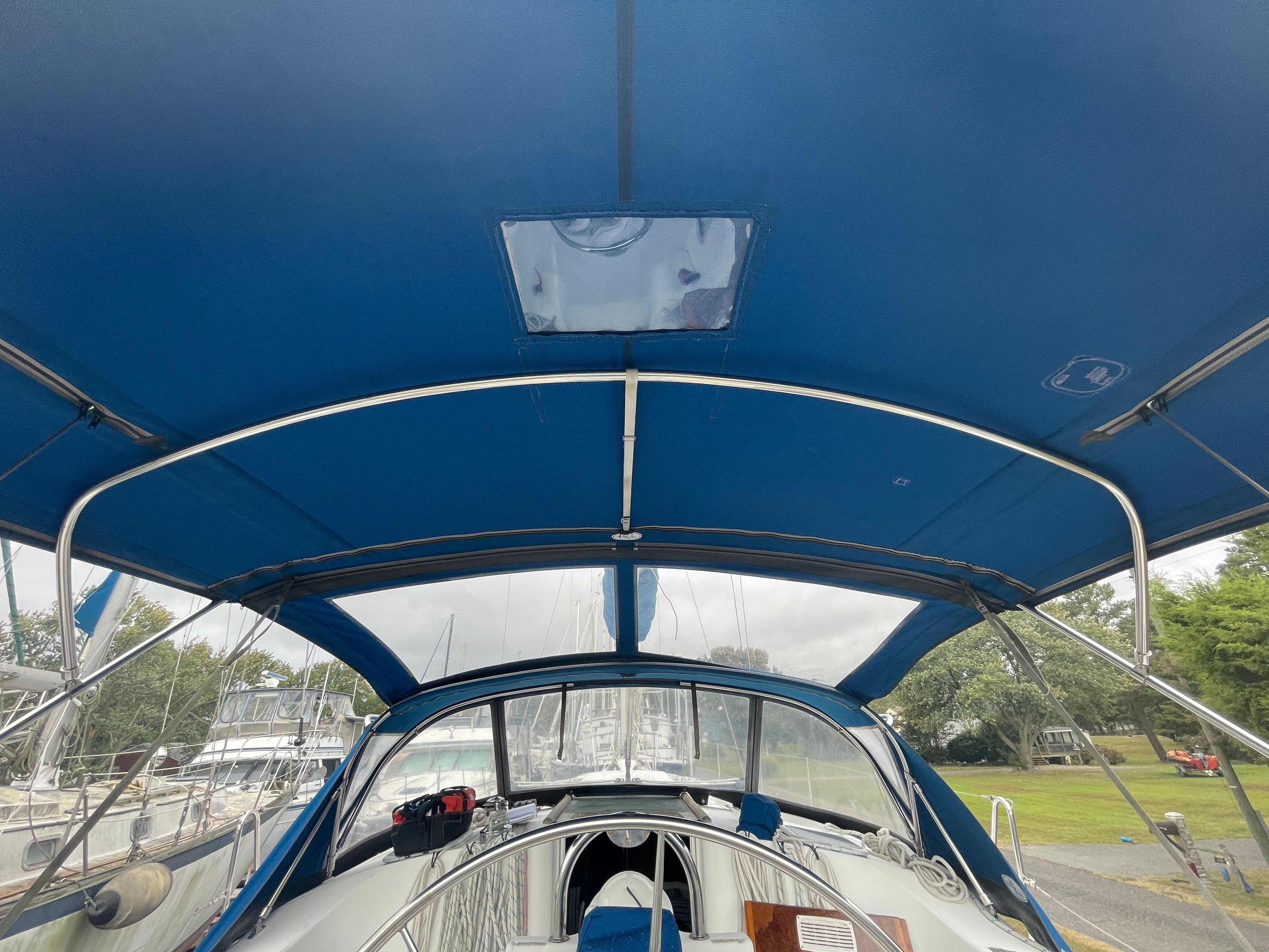 The image shows the cockpit of a Beneteau Oceanis 361 with a blue bimini top.
