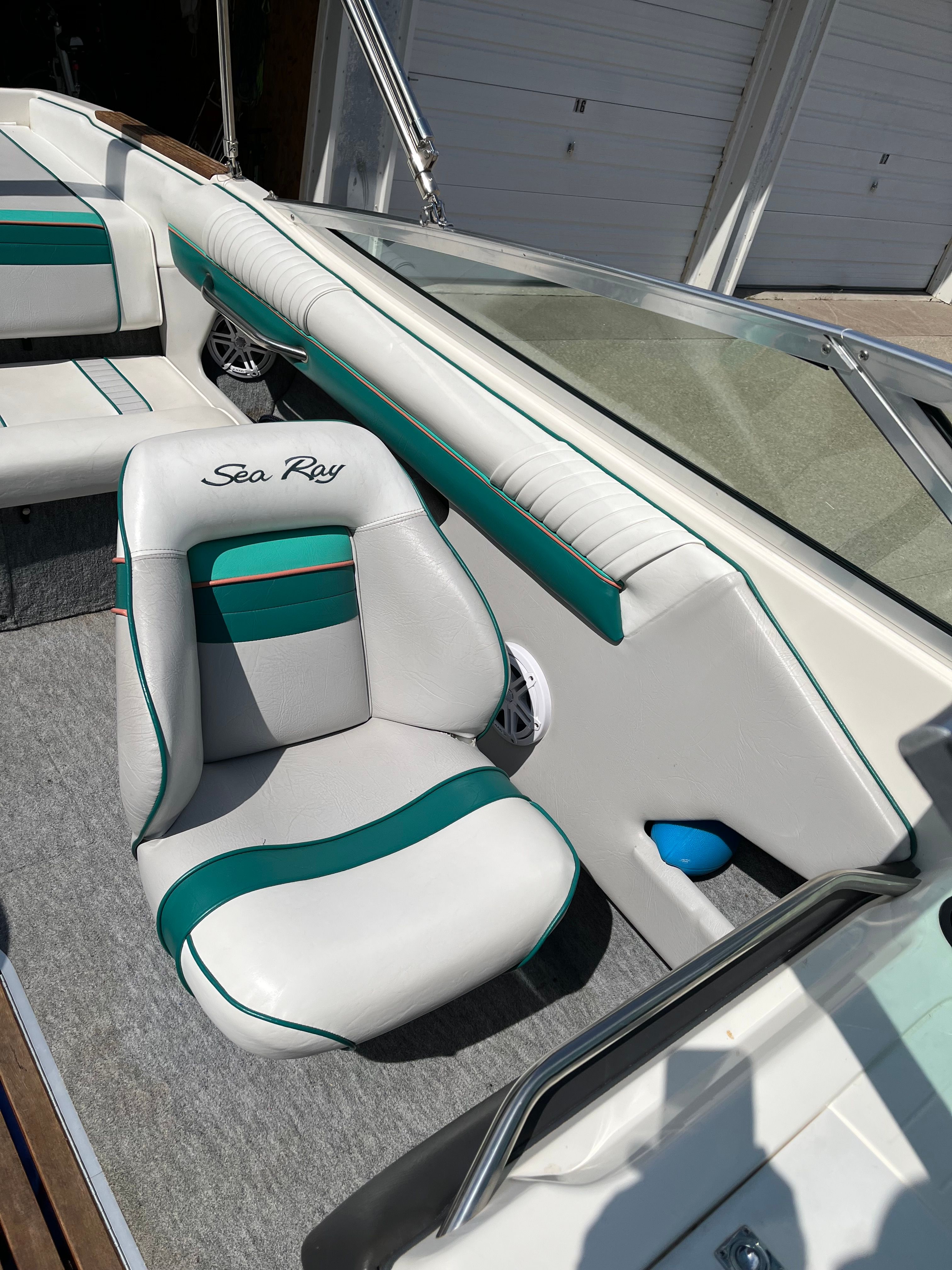 A 1992 Sea Ray 220 Bow Rider with white and green seats docked at a marina.