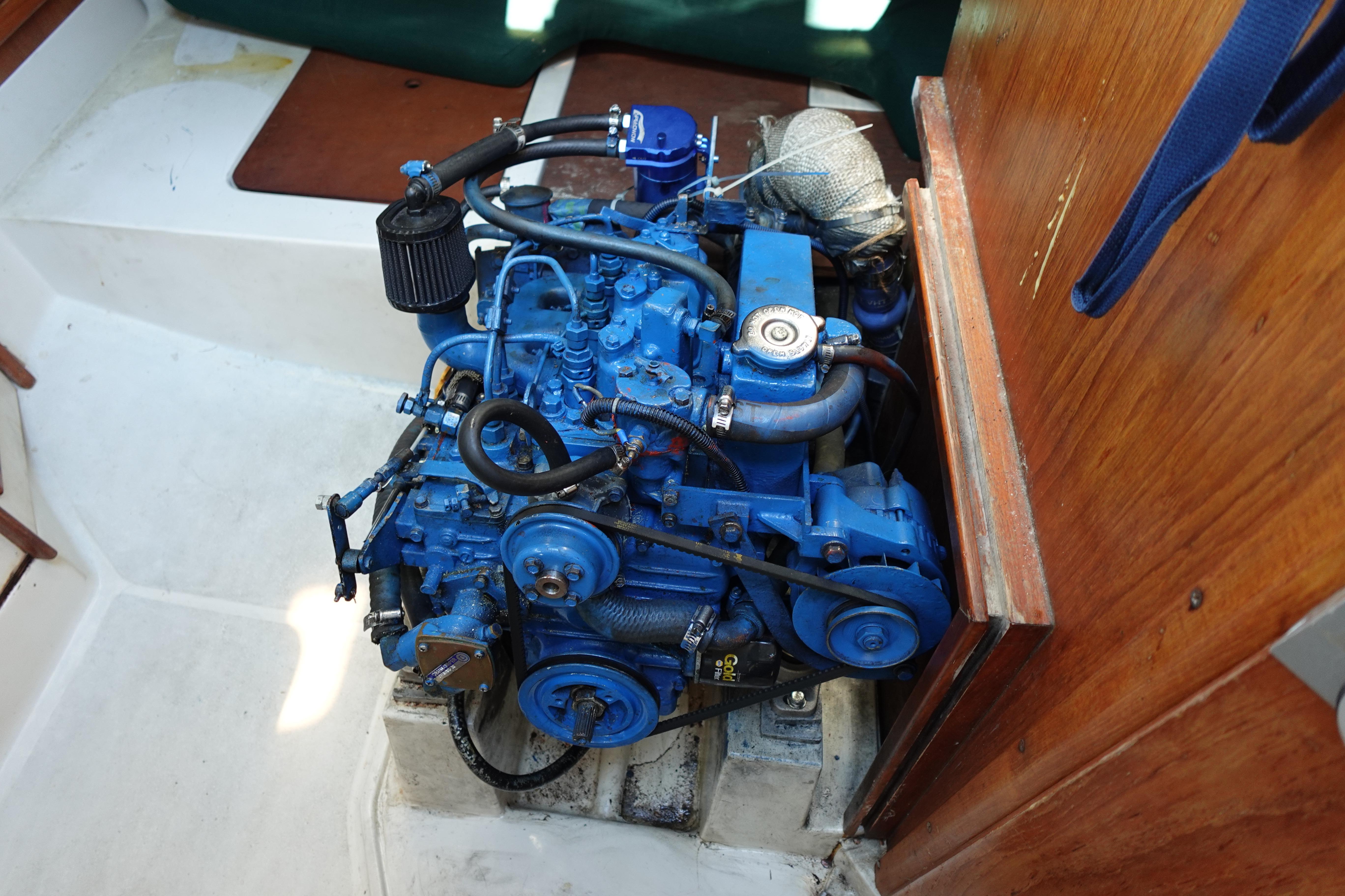 Engine of a 1997 Catalina 28 sailboat, painted blue, in a wooden compartment.