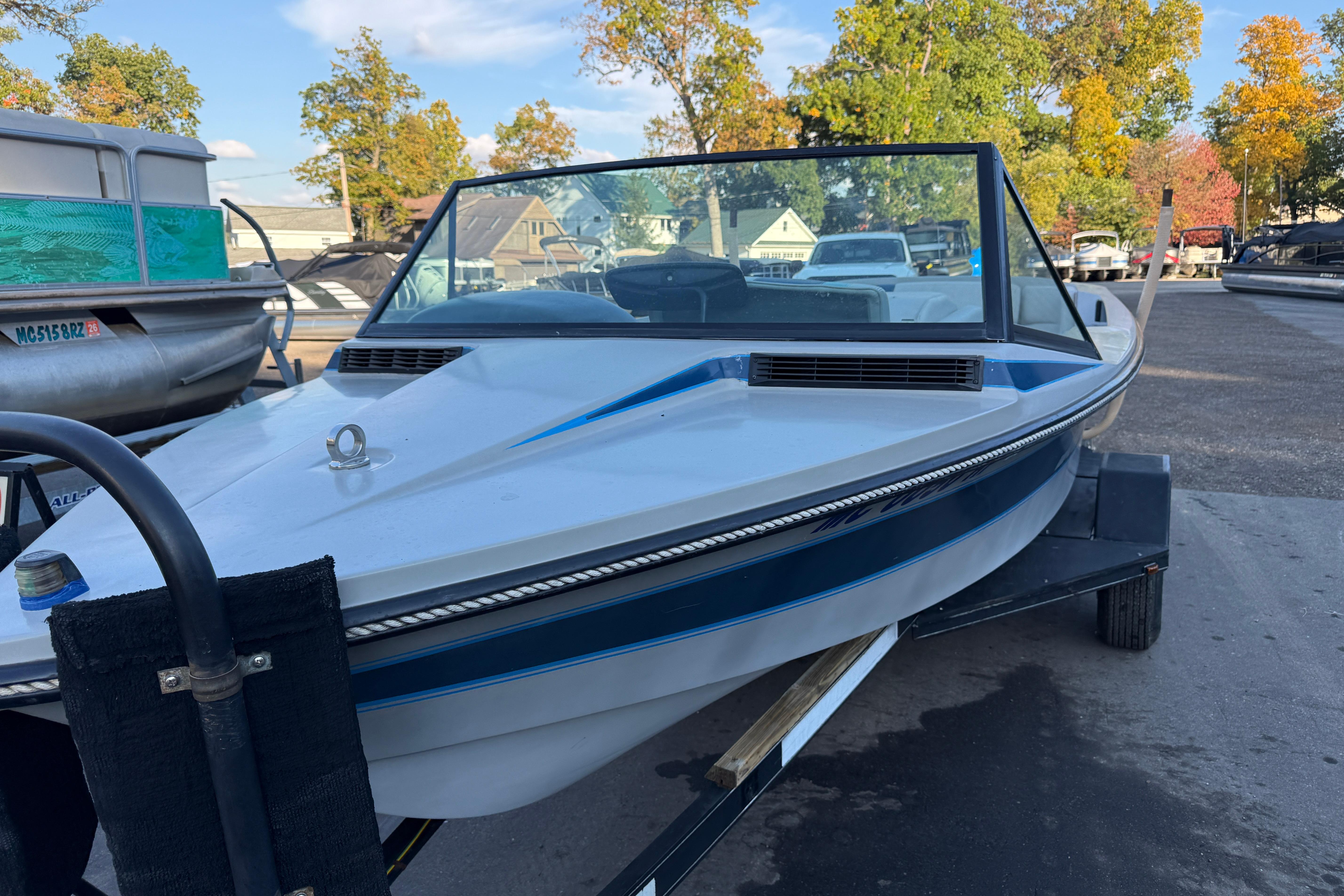 1989 Correct Craft Ski Nautique boat on trailer, parked outdoors with trees in background.