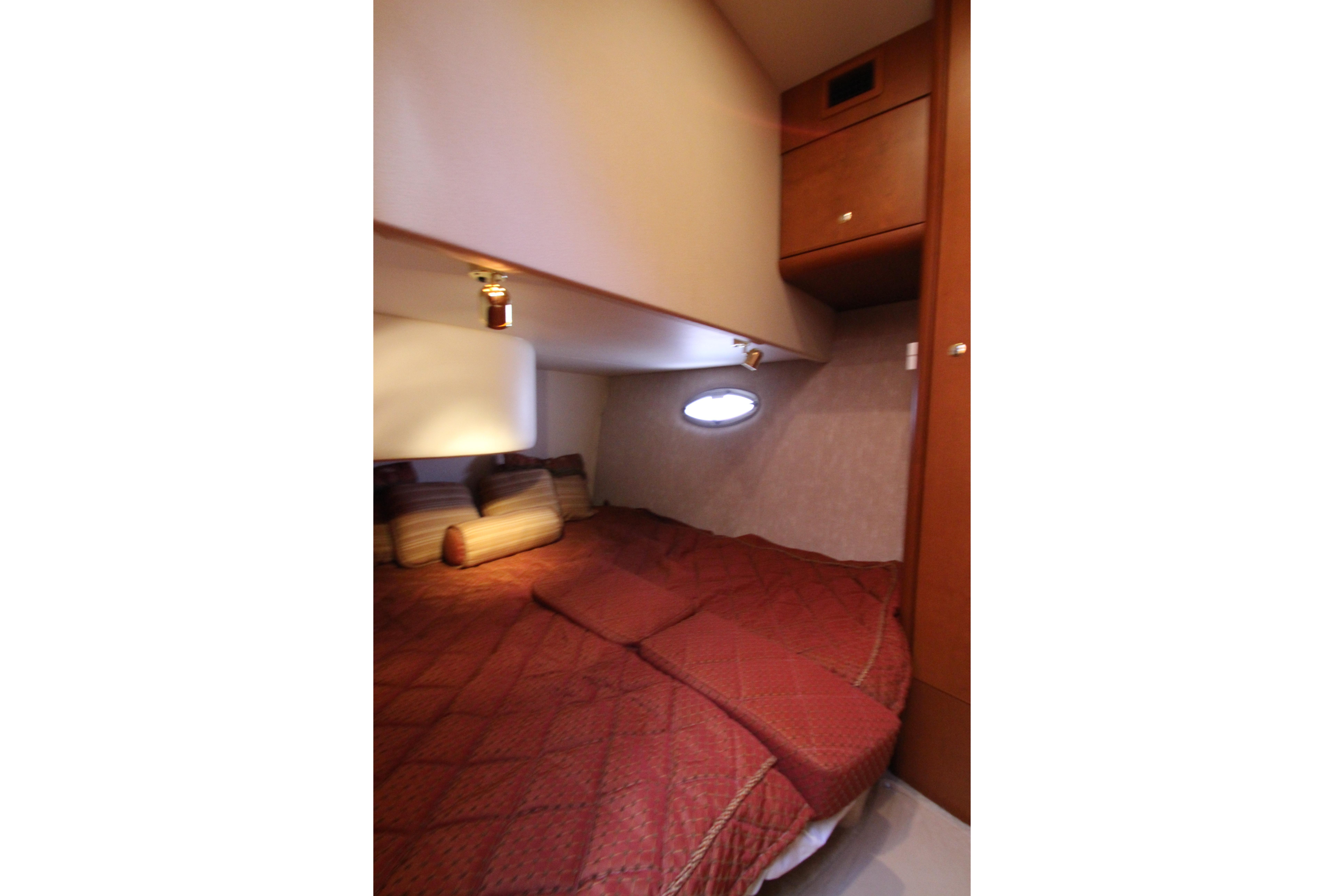 Interior cabin of 2006 Silverton 38 Sport Bridge with cozy bed and porthole window.